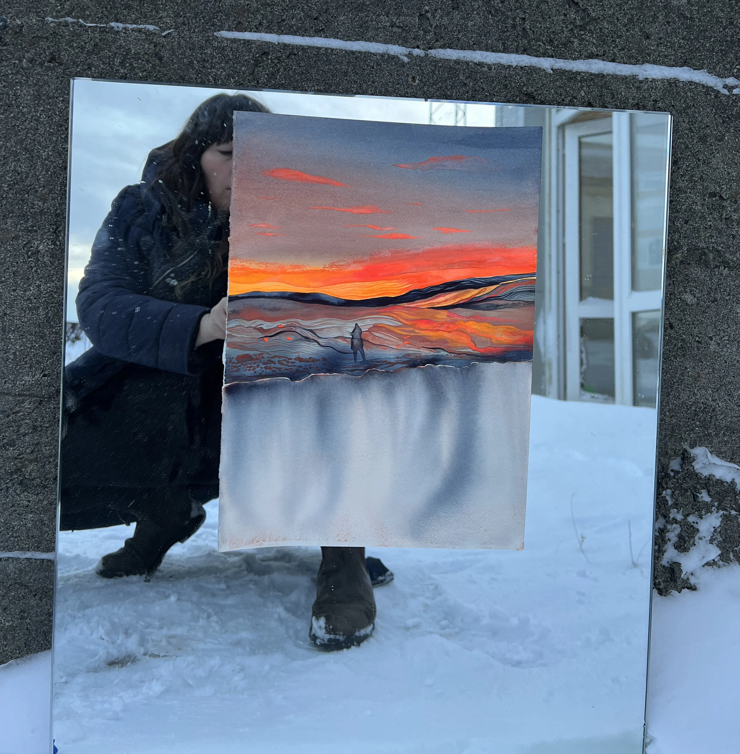 Reflection of a woman taking a photo of a painting of a sunset landscape in a mirror on the snow.