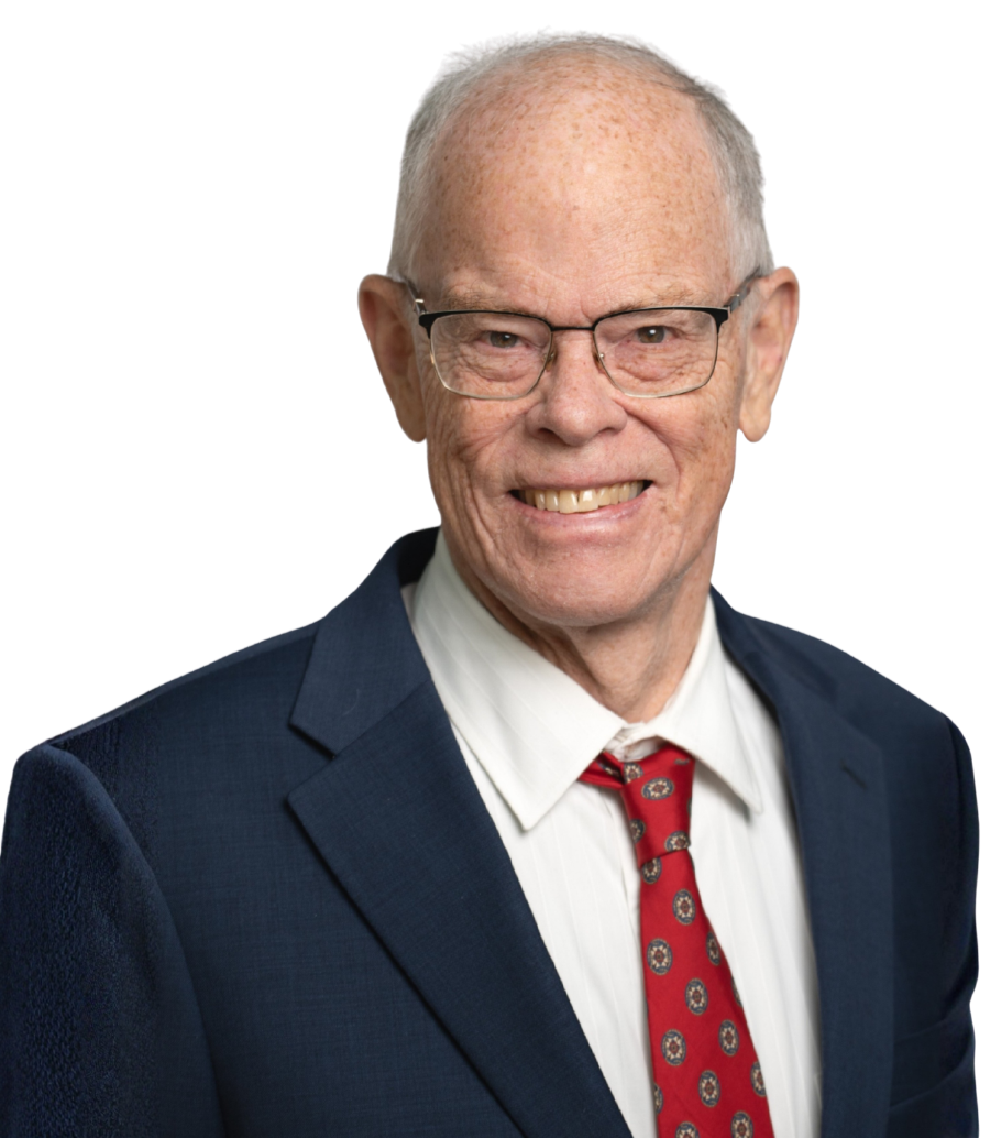 Peter Soule with glasses, wearing a dark suit, white shirt, and red tie, smiling at the camera.