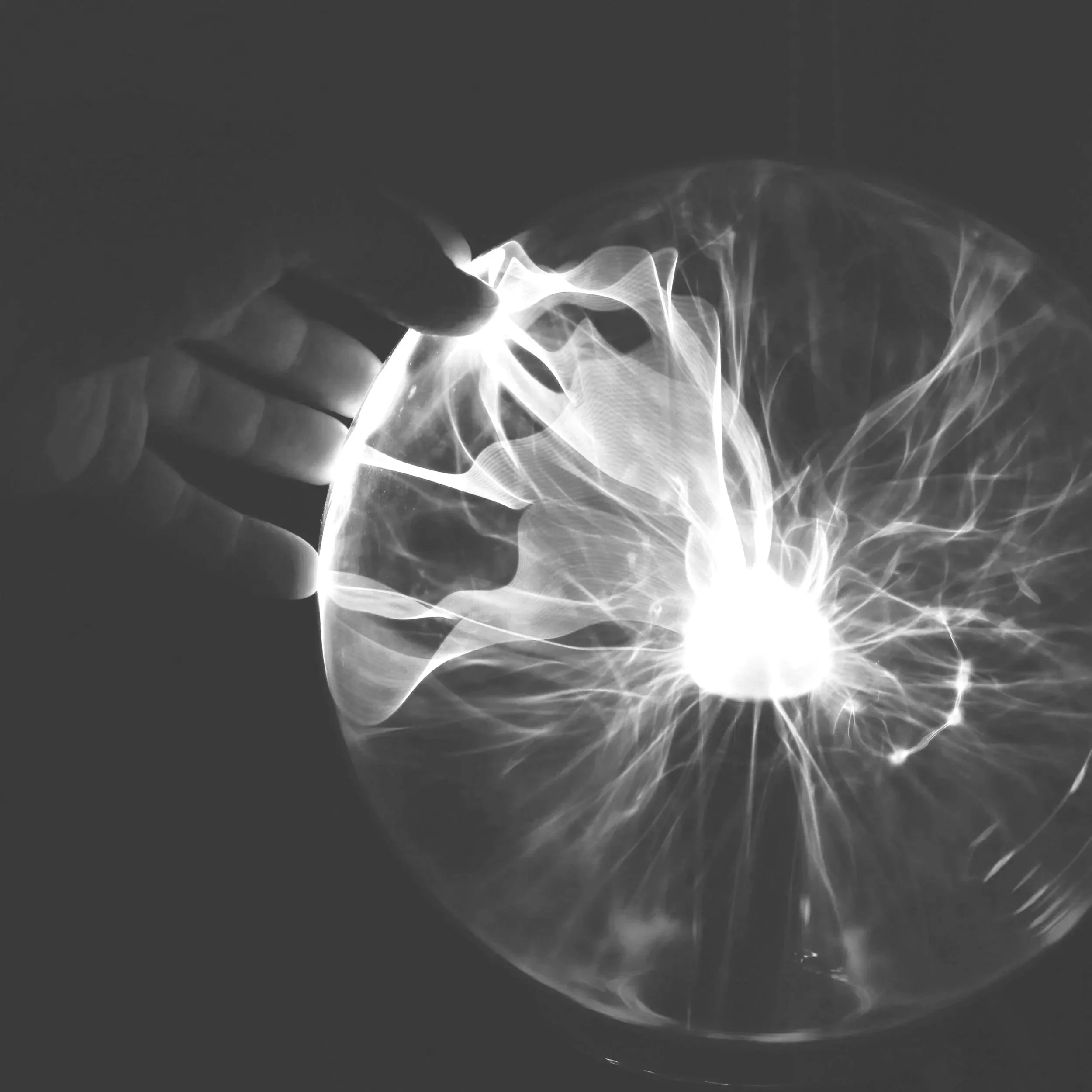 A hand holding a glass sphere that contains a lightning storm or electrical discharge inside.