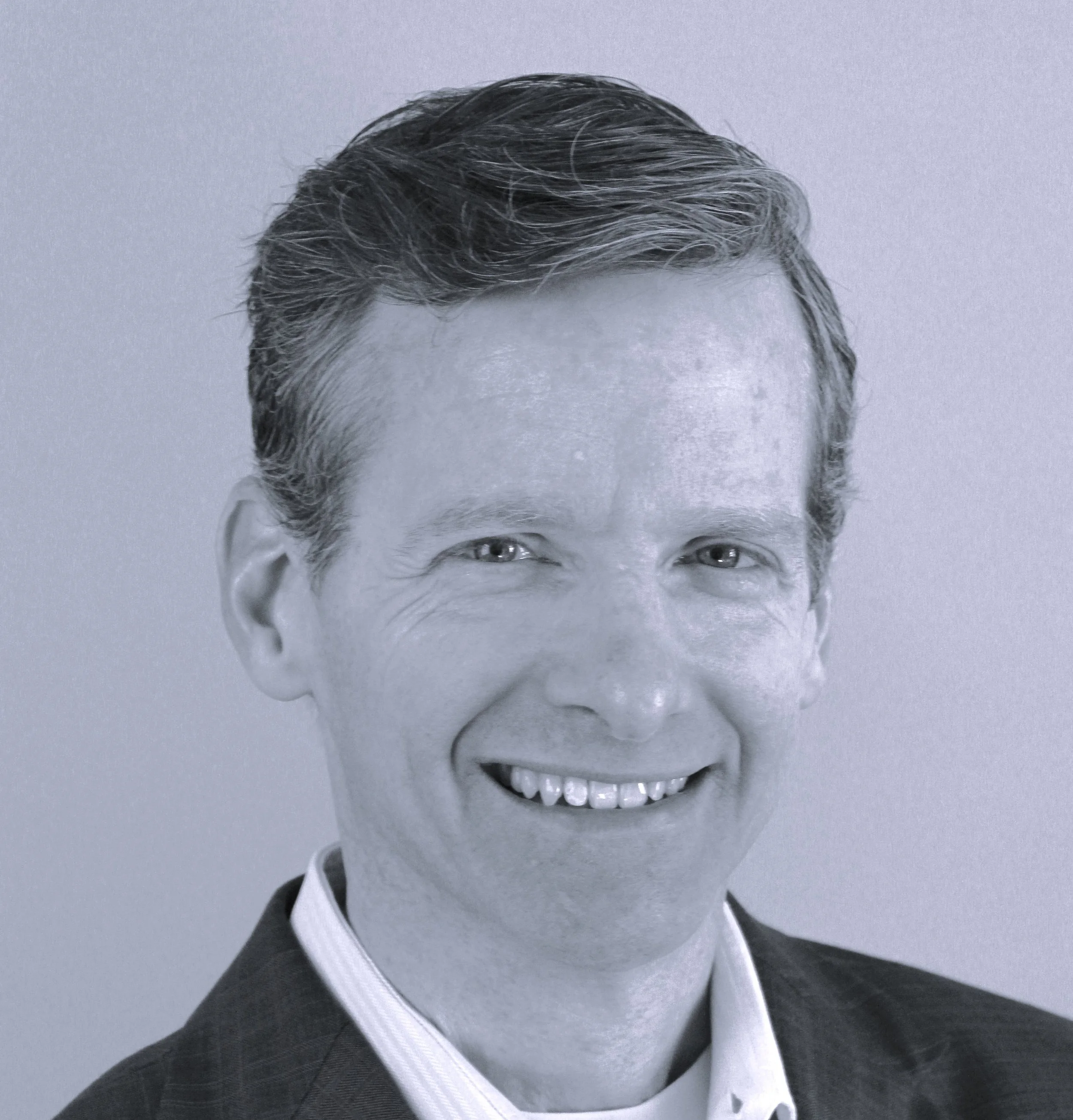 Black and white portrait of a smiling man wearing a suit.