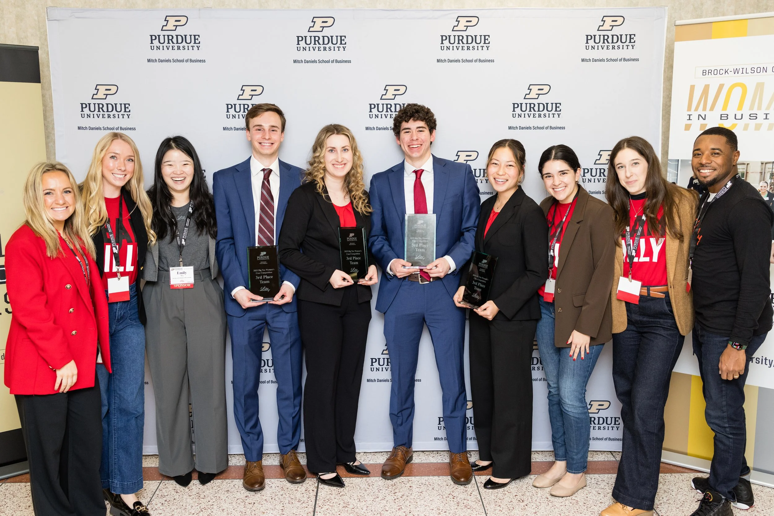 Group of students and faculty at Purdue University Mitch Daniels School of Business holding awards during an event, posing for a photo in front of a Purdue backdrop.