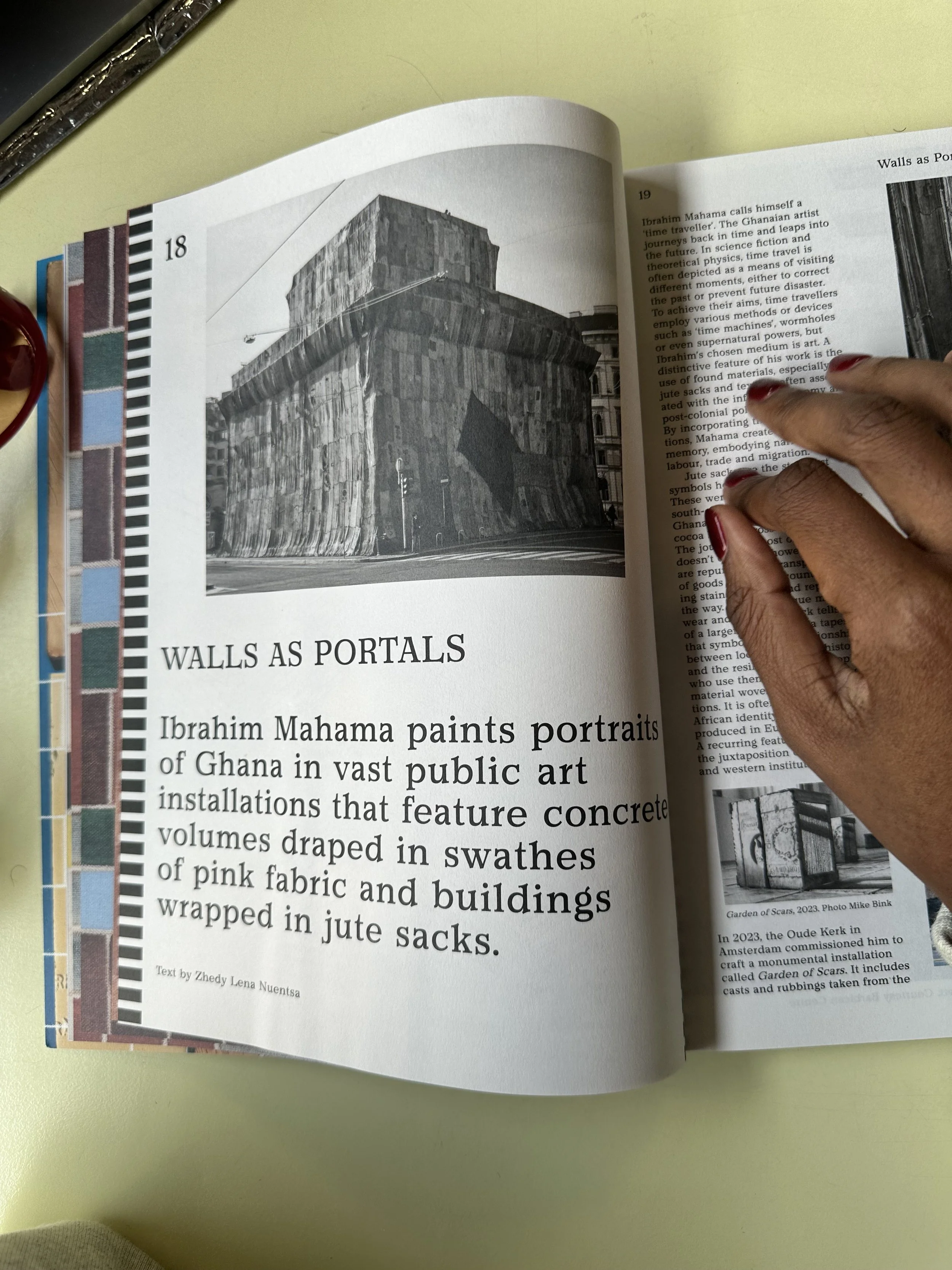 Page d'un livre avec une photographie en noir et blanc d'un bâtiment recouvert de tissus de jute, avec un texte en français décrivant l'œuvre de l'artiste Ibrahim Mahama, intitulé 'Walls as Portals'.