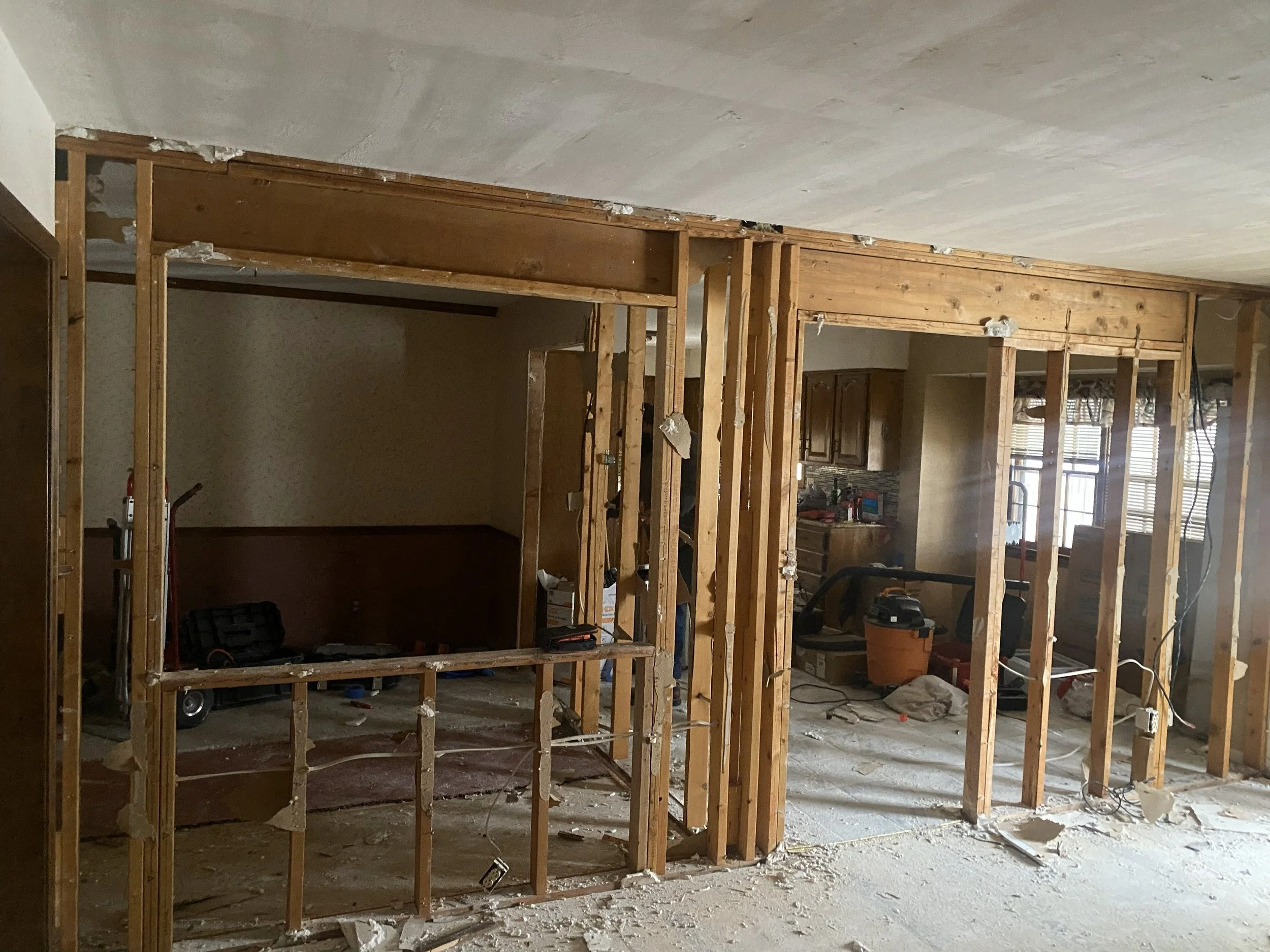 Interior of a house under renovation with exposed wooden studs and construction equipment.