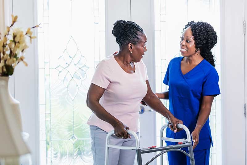 healthcare-worker-visiting-a-senior-woman-at-home-helping-her-use-a-mobility-walker.jpg