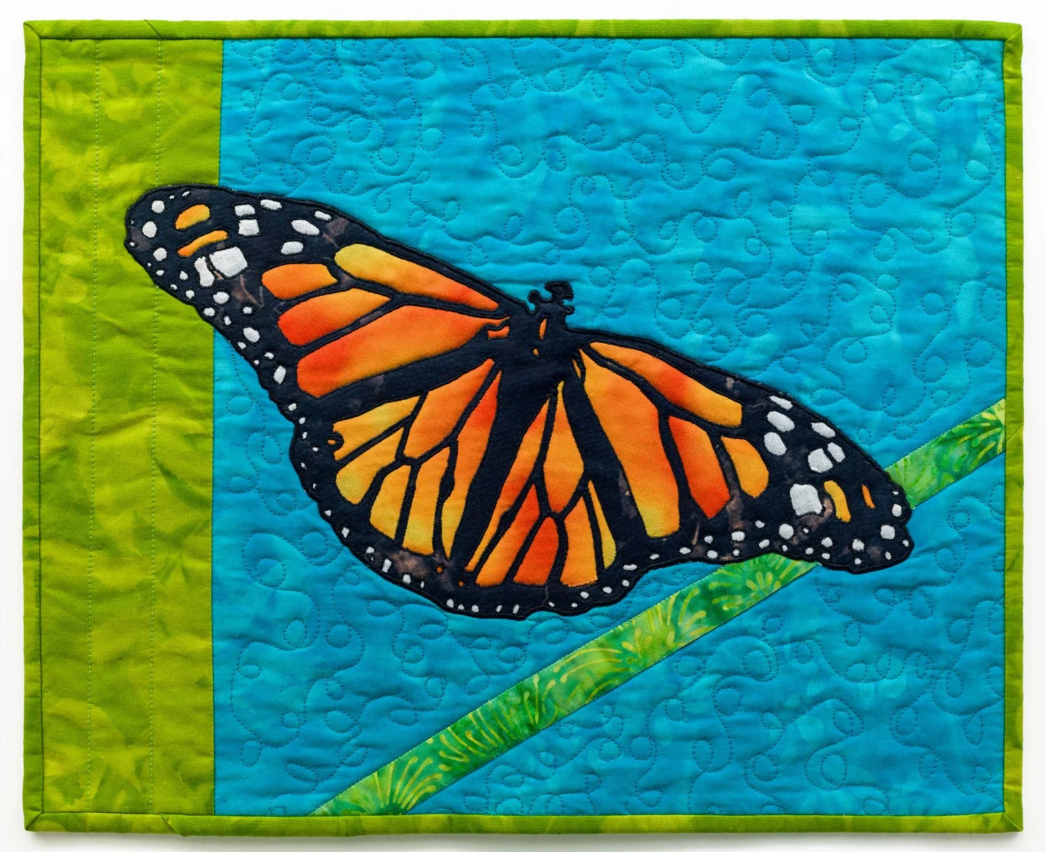 A quilt with a butterfly design on a blue and green background.