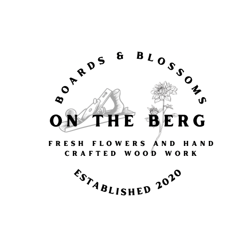 Logo for Boards & Blossoms featuring a flower and woodworking tools with text 'On the Berg' and details about fresh flowers, handcrafted woodwork, and established in 2020.
