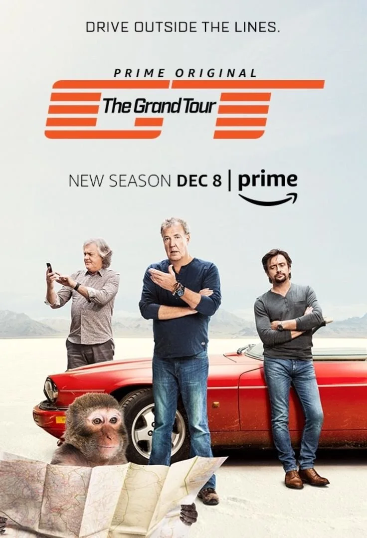 Promotional poster for Prime Original series 'The Grand Tour' featuring three men standing next to a red sports car, a chimpanzee looking at a map, and a desert background, with text promoting the new season premiering December 8 on Prime.