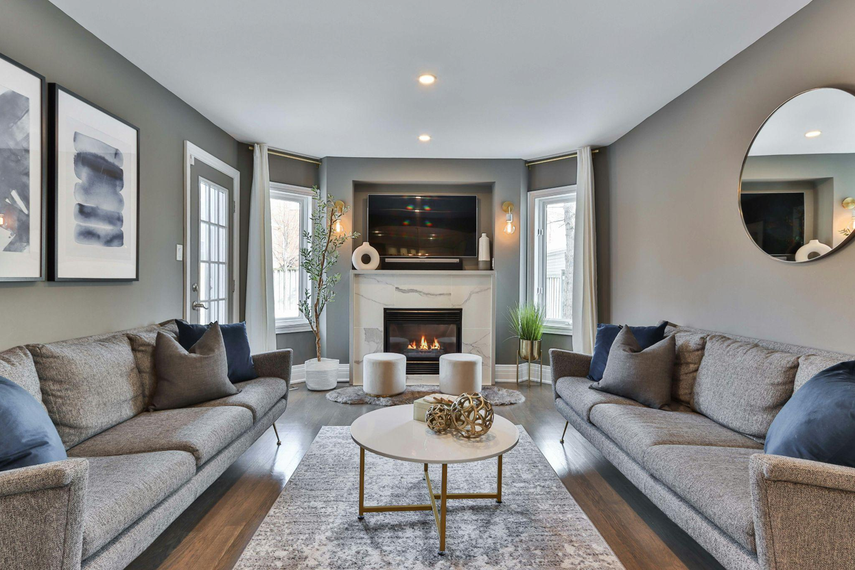 Bright living room with white sofas, two armchairs, a wood coffee table, large vaulted ceiling, black fireplace, and artwork on the walls.