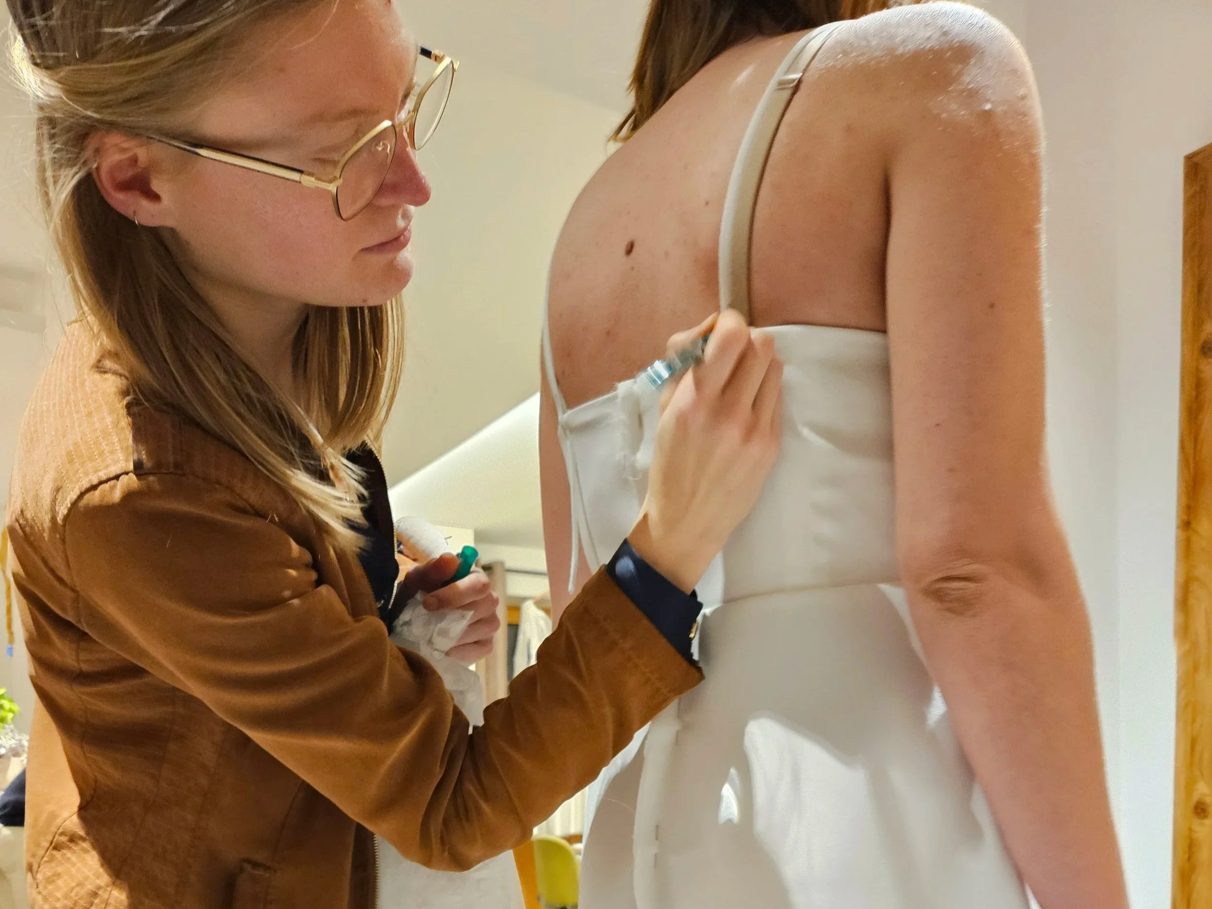 Une petite fille regarde Solenne, créatrice de robe de mairée sur mesure, travaillant au ras du sol, pour ajuster la longueur de la robe de mariée_Maison d'Héra 