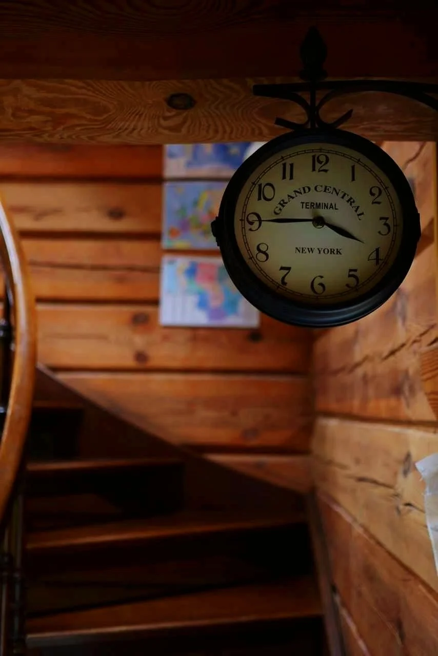 A round clock hanging on a wooden wall showing the time as 3:48, labeled 'Grand Central Terminal, New York.'