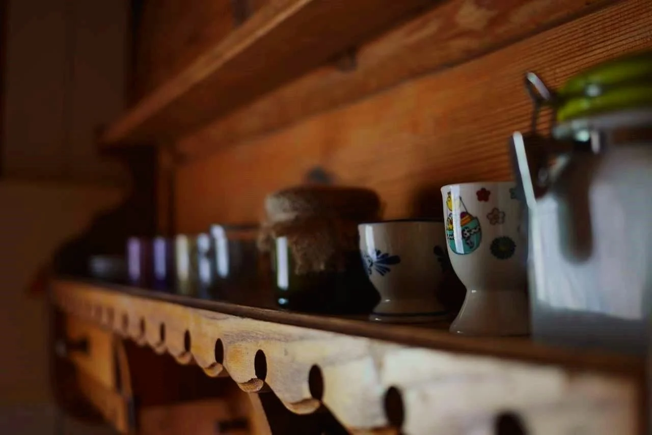 Close-up of decorative ceramic cups on a wooden shelf.