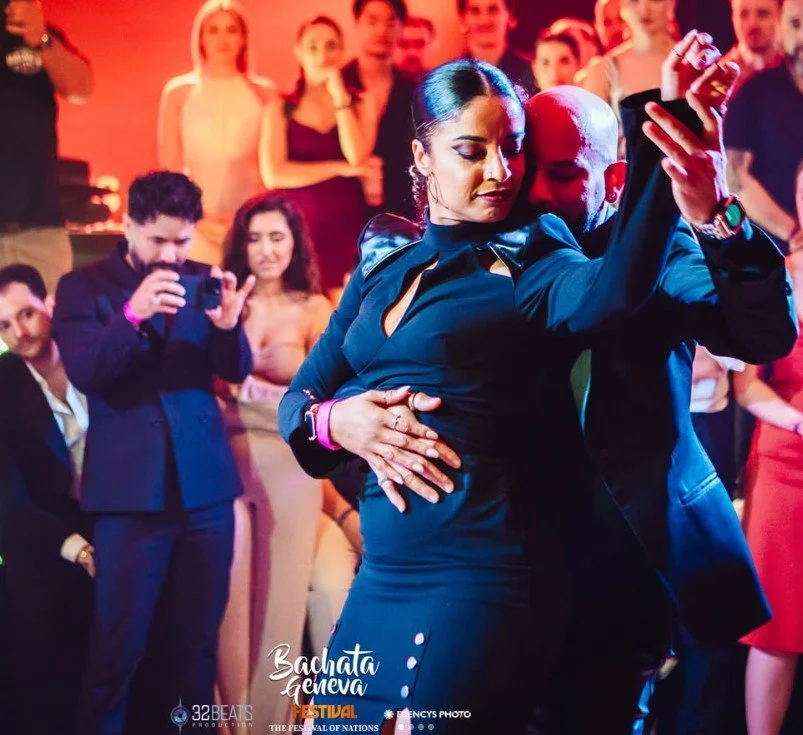 Ataca & La Alemana dancing closely at a Bachata festival, surrounded by an audience watching and taking photos.