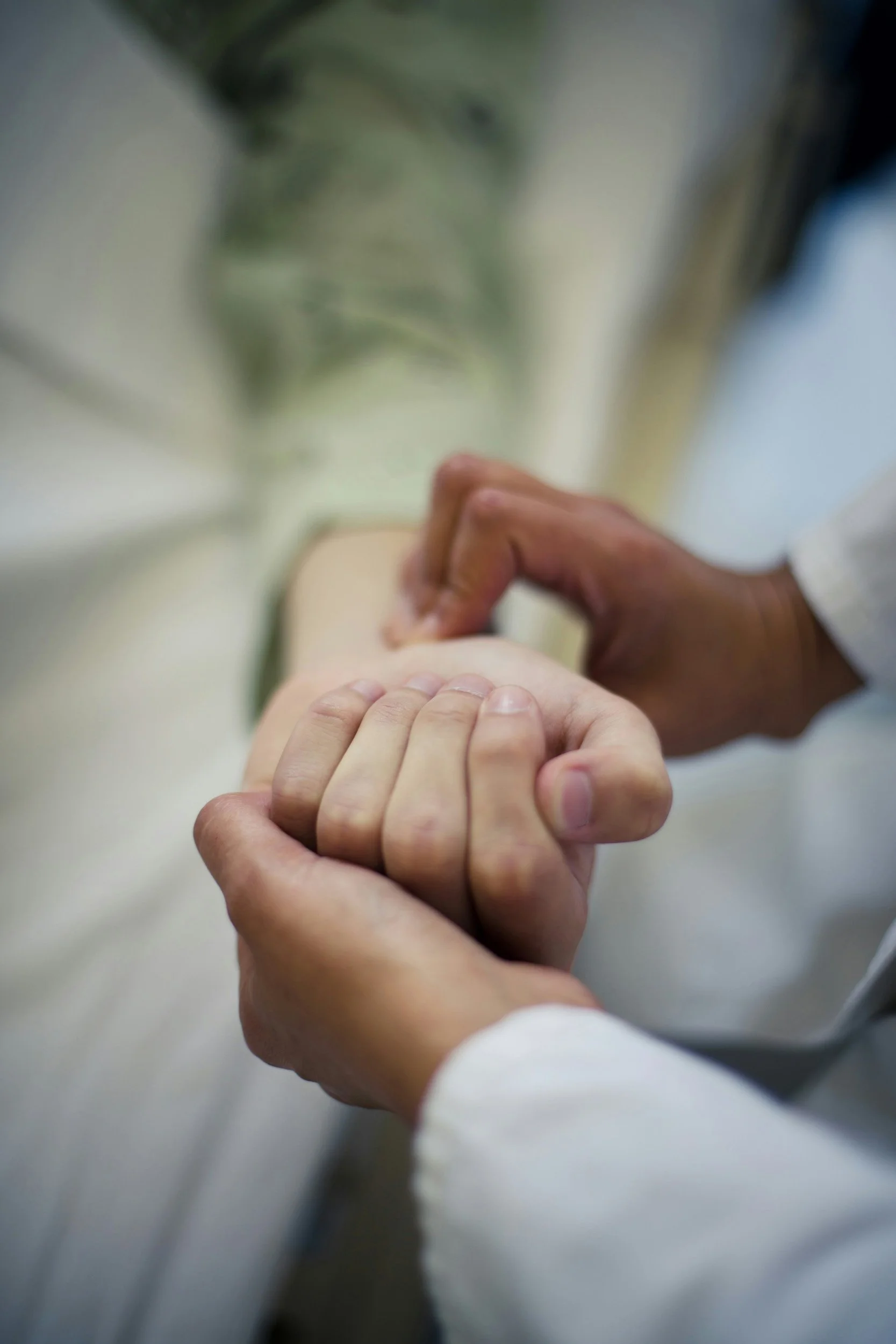 Clinician holding a patient’s hand during a healthcare interaction.