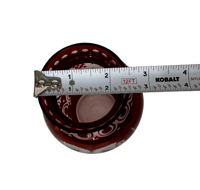 Top view of a vintage ruby-flashed glass vase with a tape measure showing an opening of approximately 2.5 inches
