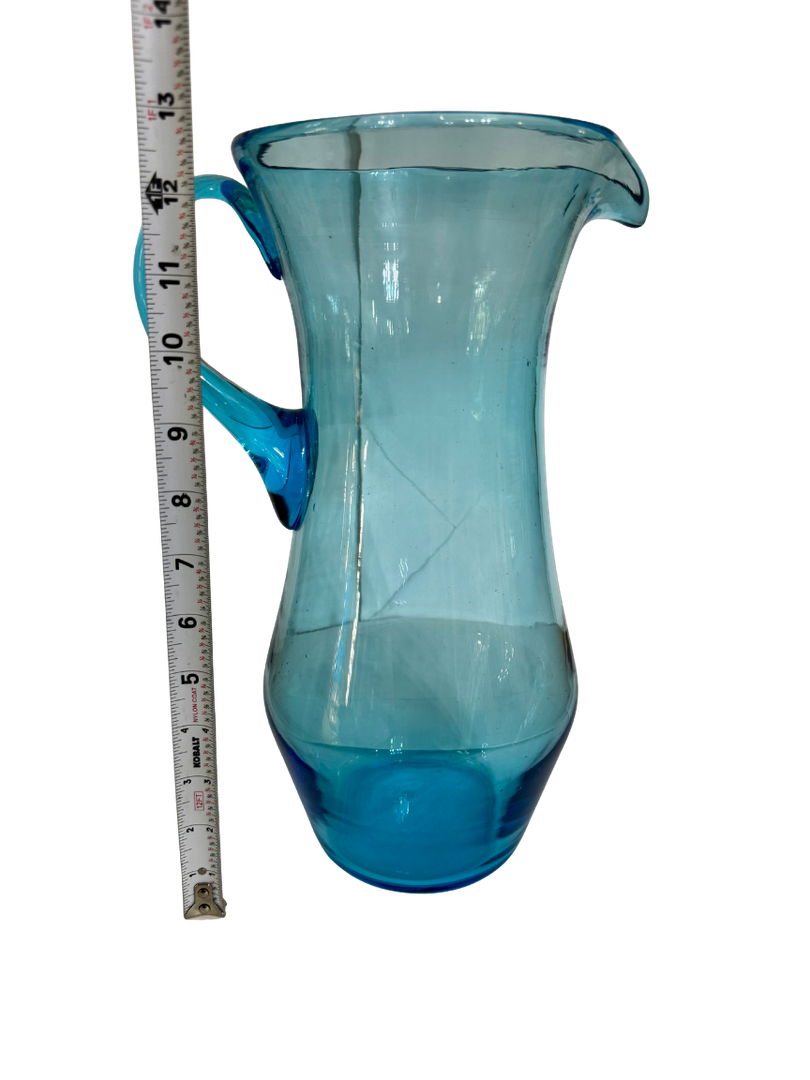 Antique hand-blown aqua glass pitcher beside a tape measure showing an approximate 12.5-inch height
