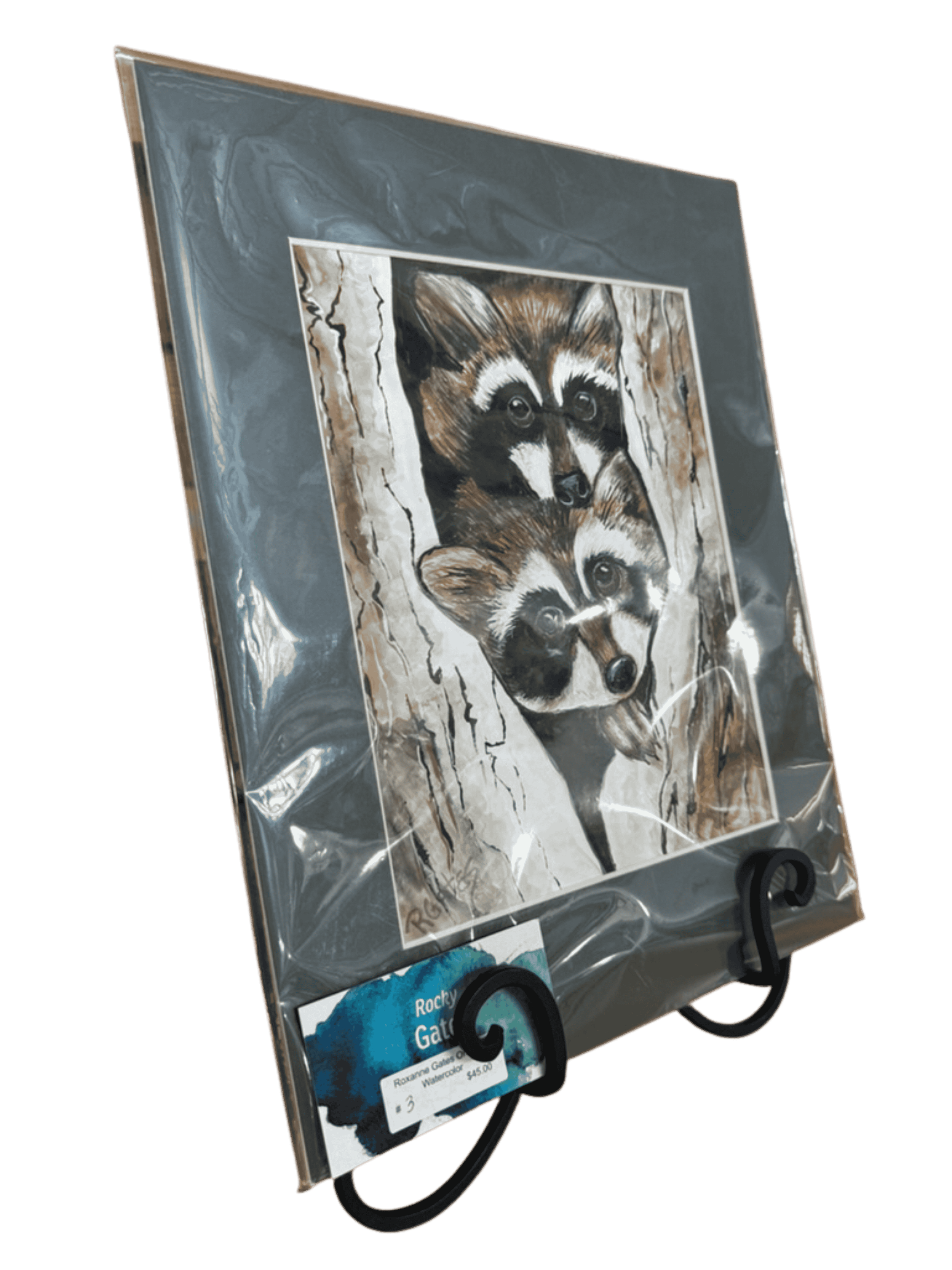 Angled view of raccoon wildlife watercolor painting by R. Gates with two raccoons in hollow tree.