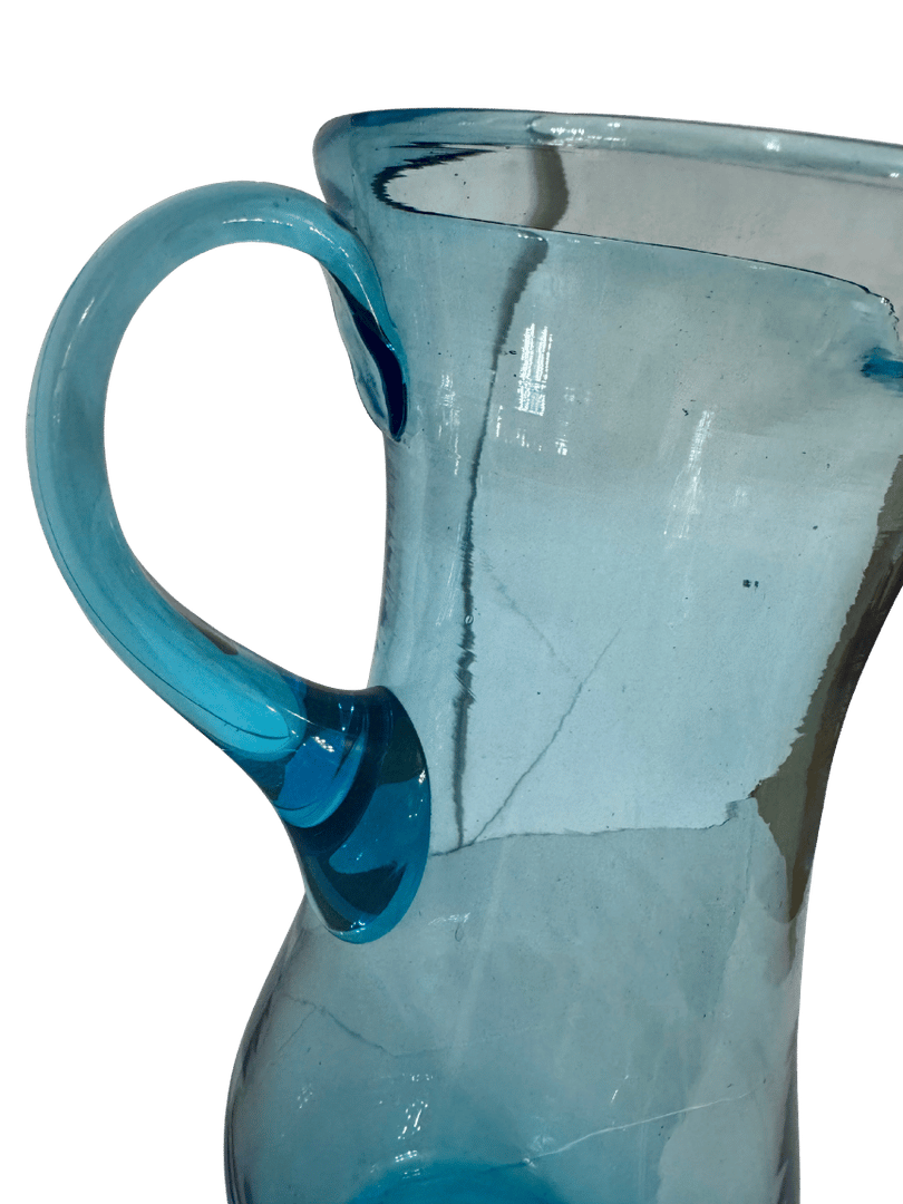 Close-up of the applied loop handle on an antique hand-blown aqua glass pitcher, showing the deeper blue glass attachment points
