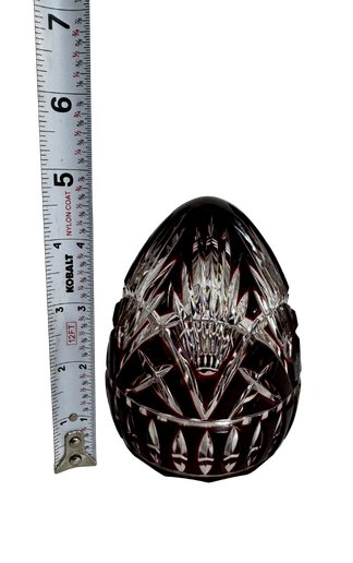 Vintage Hungarian ruby cut-to-clear crystal egg beside a tape measure showing a height of approximately four inches