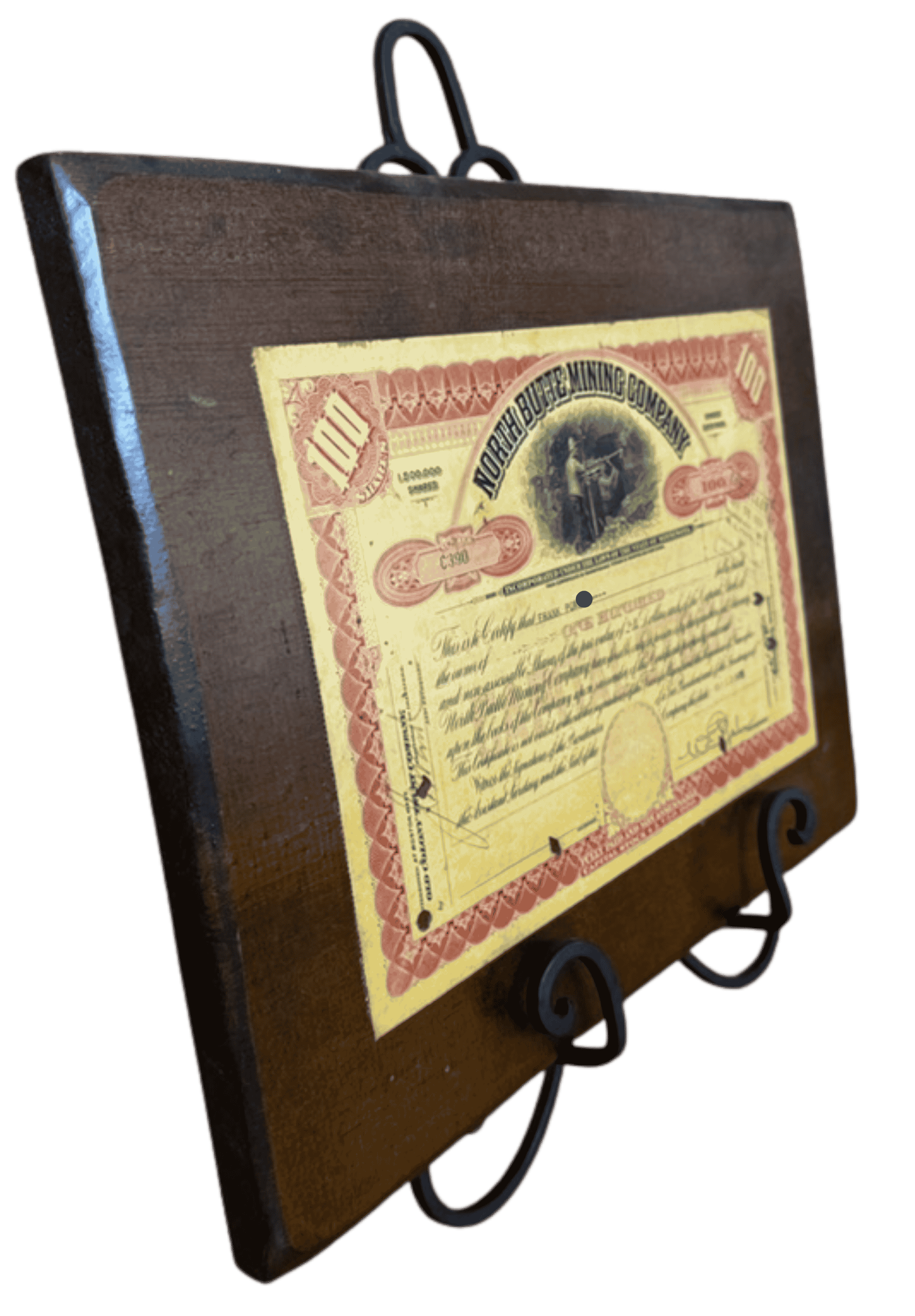 Angled view of North Butte Mining Company certificate plaque showing antique stock certificate mounted on dark wood display board.