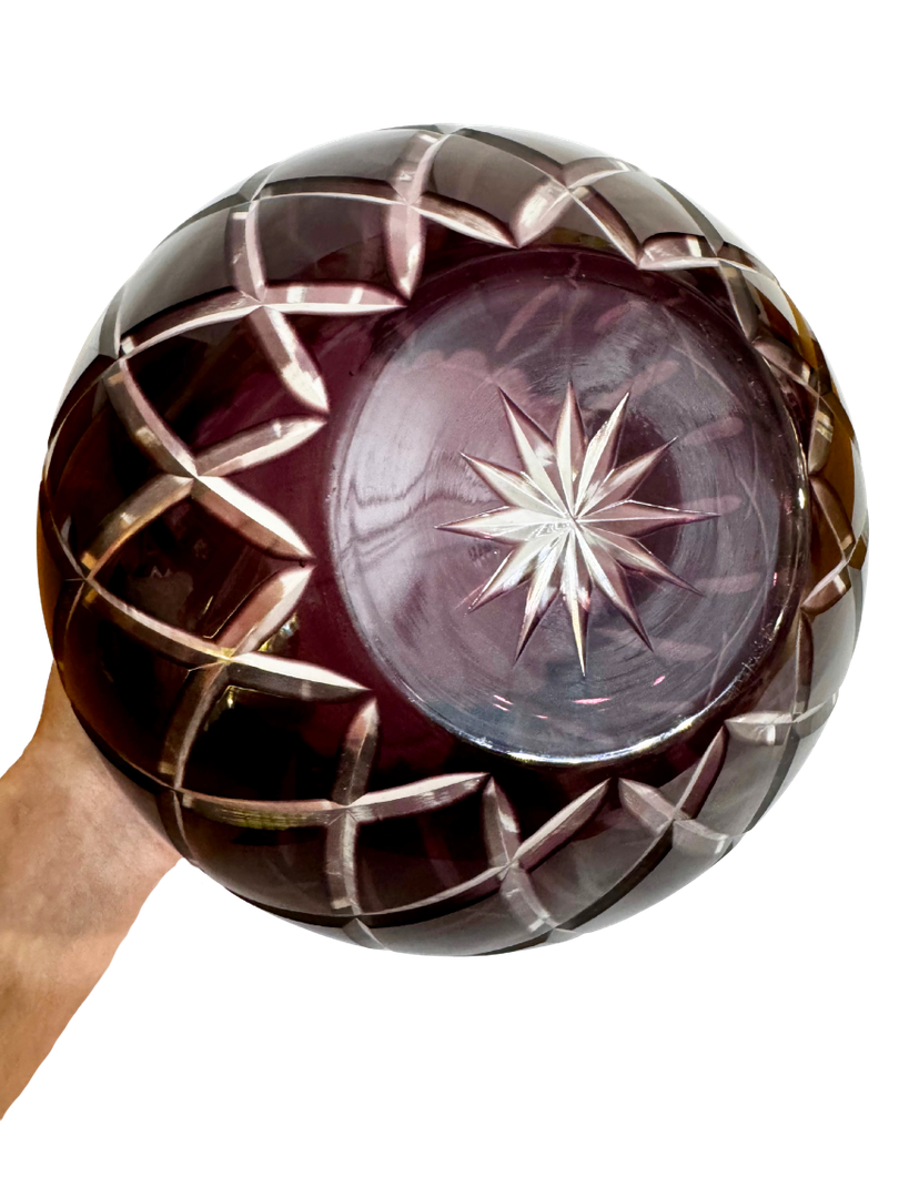 Underside of a vintage amethyst cut-to-clear crystal bowl showing its radiant starburst and geometric cutting