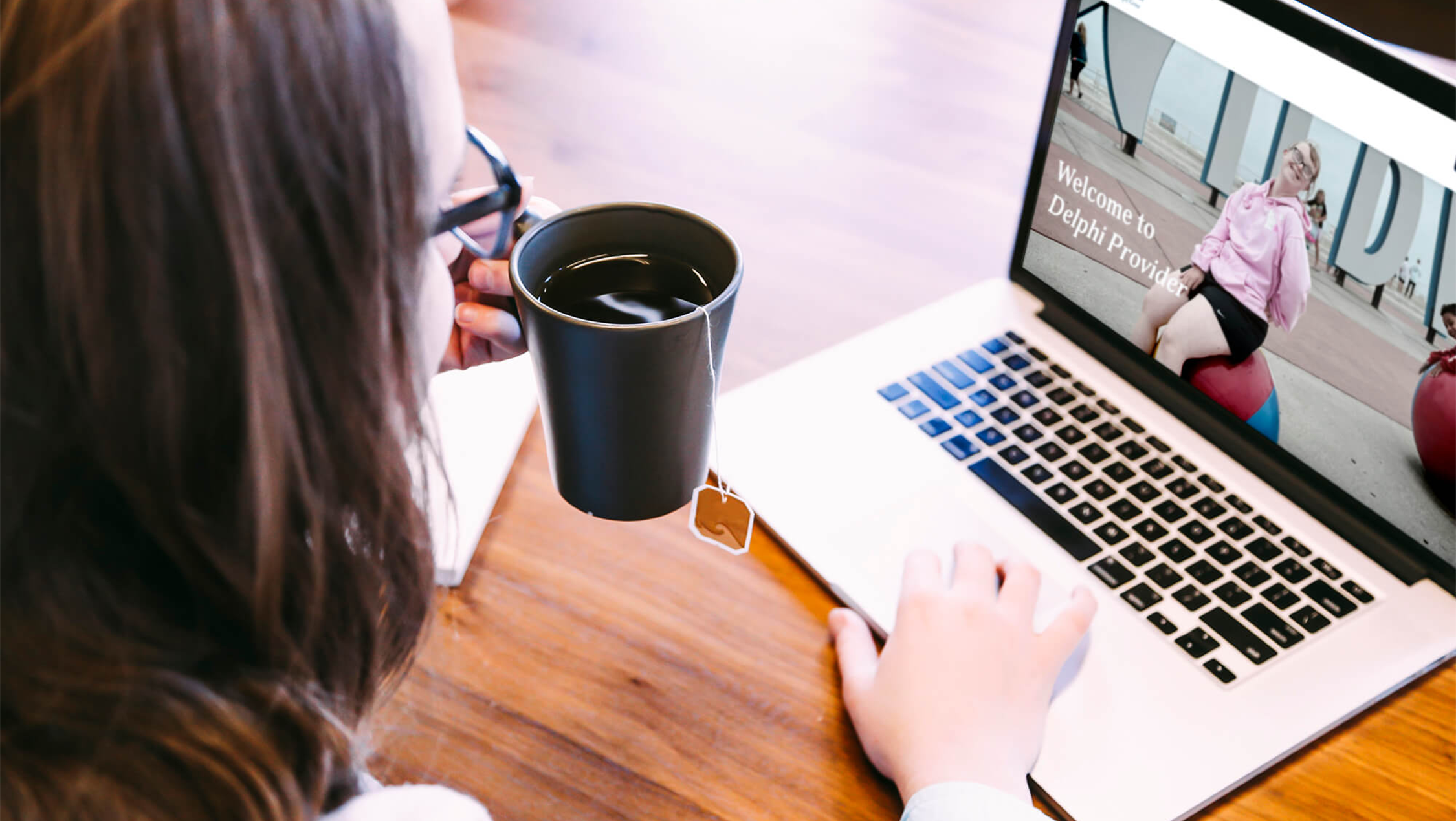 Woman with hot tea on Delphi Provider website on laptop