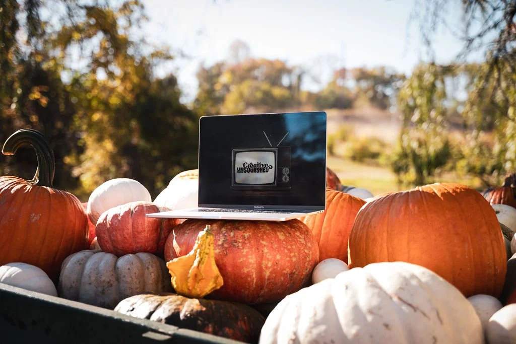 Laptop with the creative unsquashed logo on it, sitting on a wagon full of pumpkins and gourds