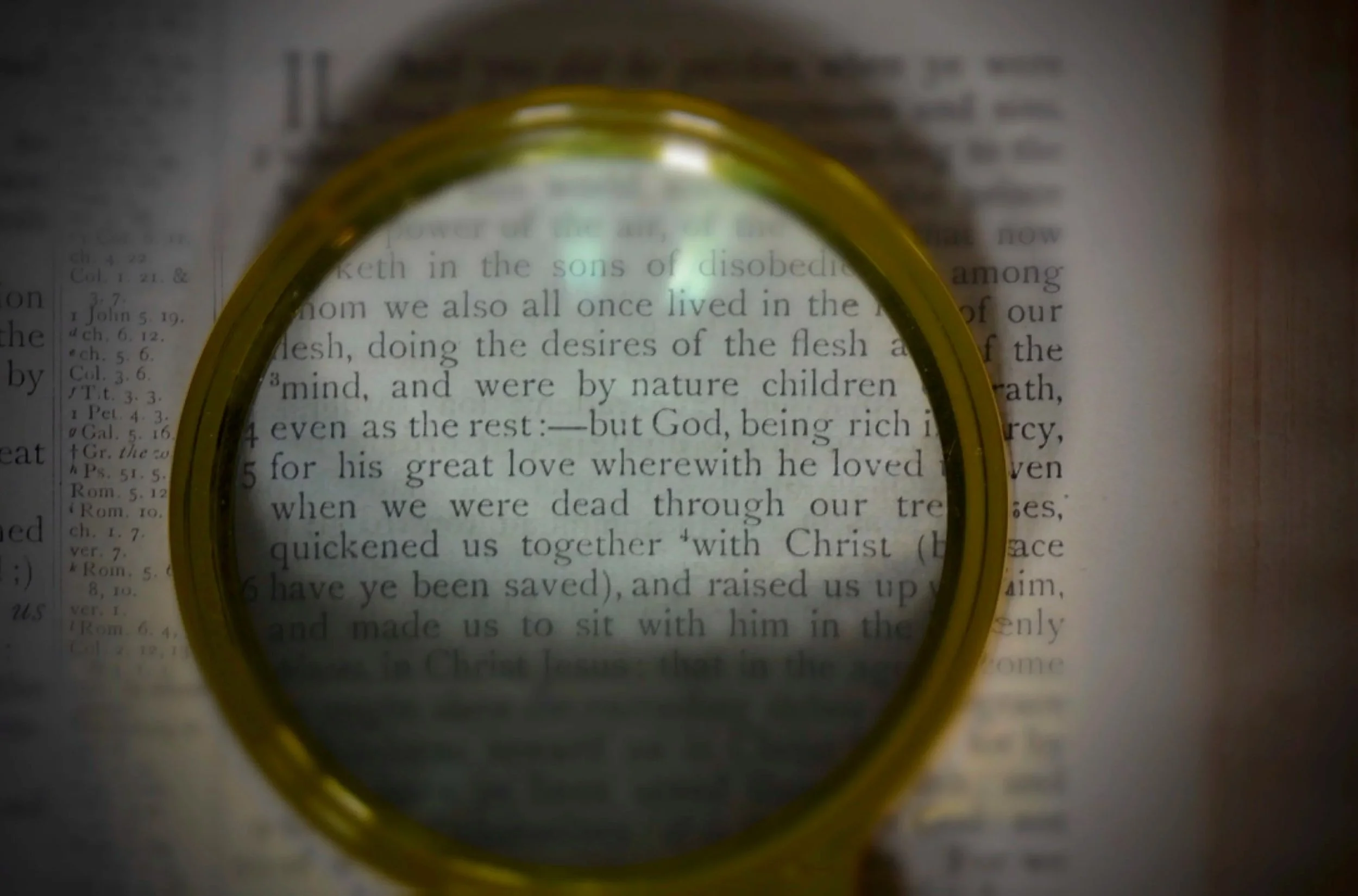A magnifying glass placed over a page of a book, focusing on a section of the text.