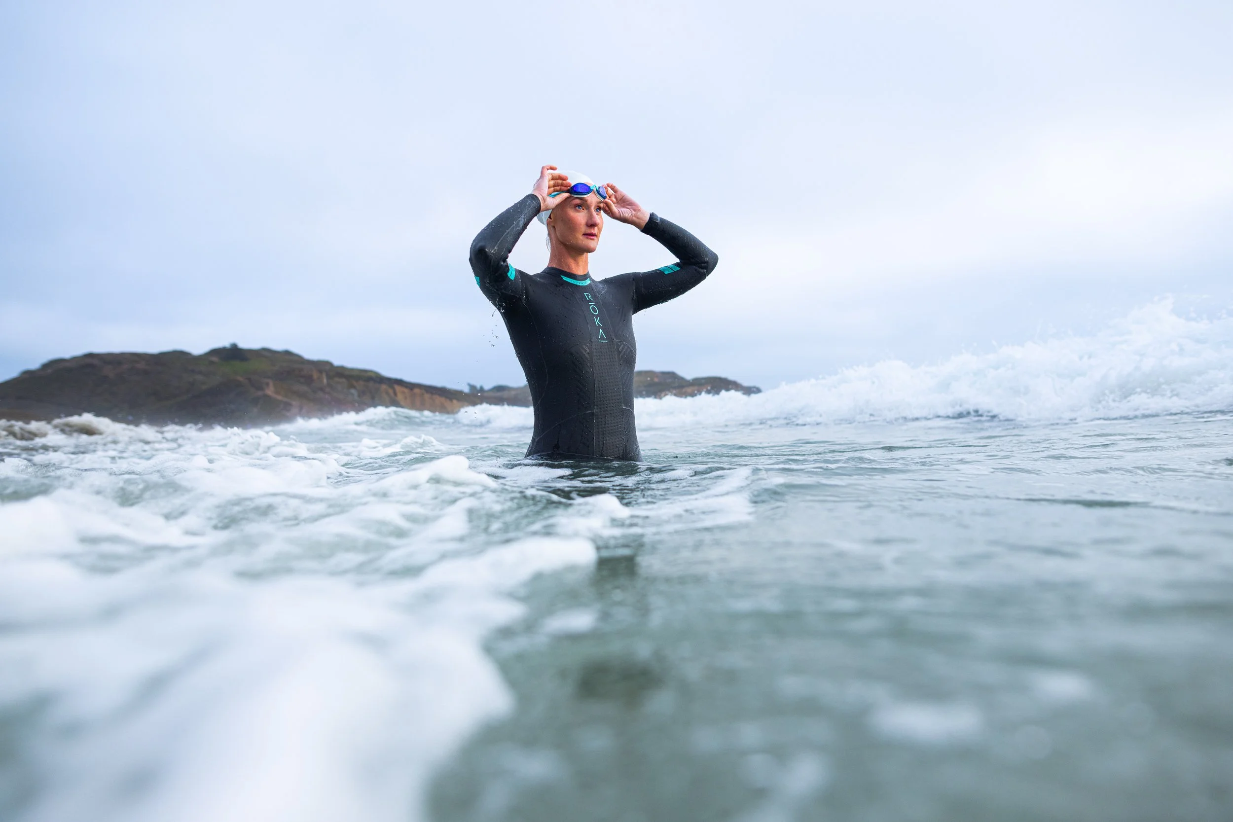 Woman in a wetsuit adjusting her goggles in the ocean