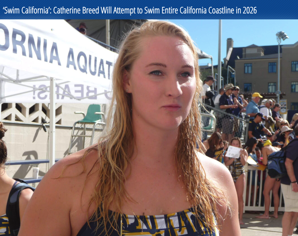 A young woman with wet blonde hair standing outdoors at a swim event, with many people and a building in the background.