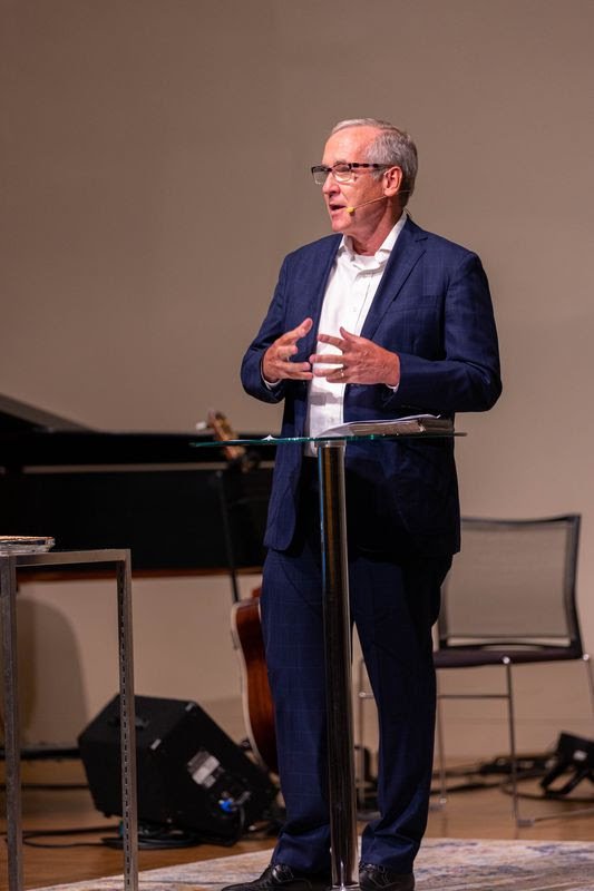 David Bisgrove speaks at a podium in a conference or seminar setting.