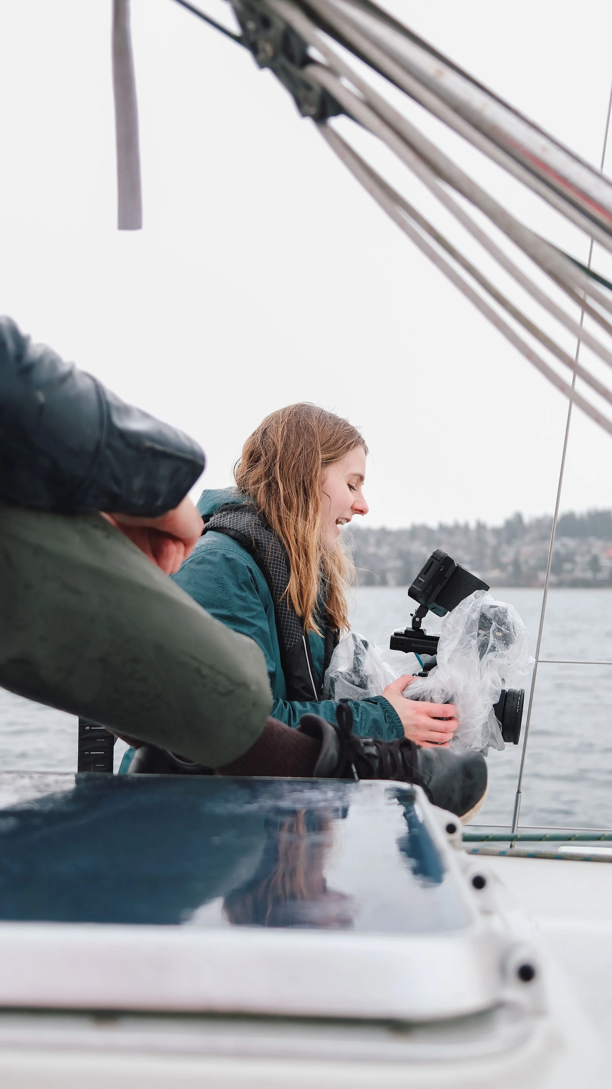 A woman on a boat operating a camera with a stabilizer, Vancouver, BC. Video production and documentary storytelling. 