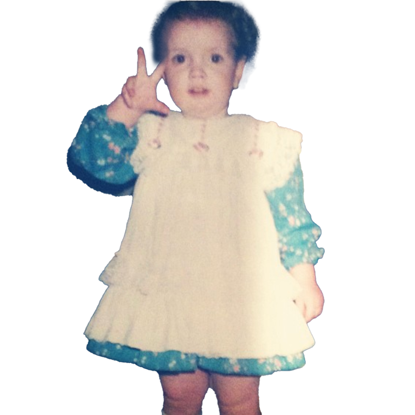 A young girl with curly hair making a peace sign with her right hand while standing.
