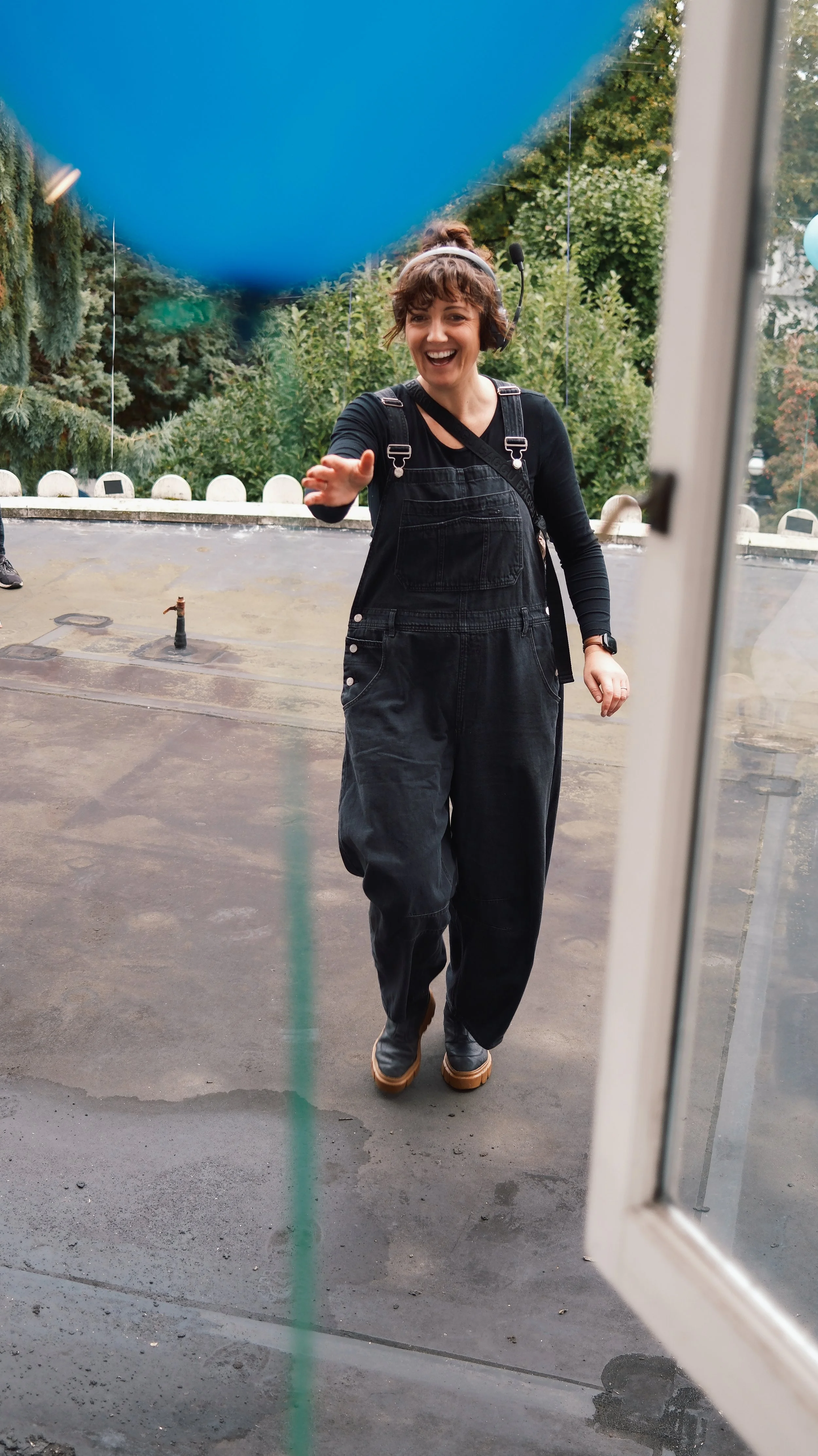 Woman smiling and reaching out to someone through a glass door from outside.