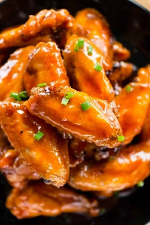 Close-up of buffalo chicken wings covered in sauce and garnished with chopped green onions.