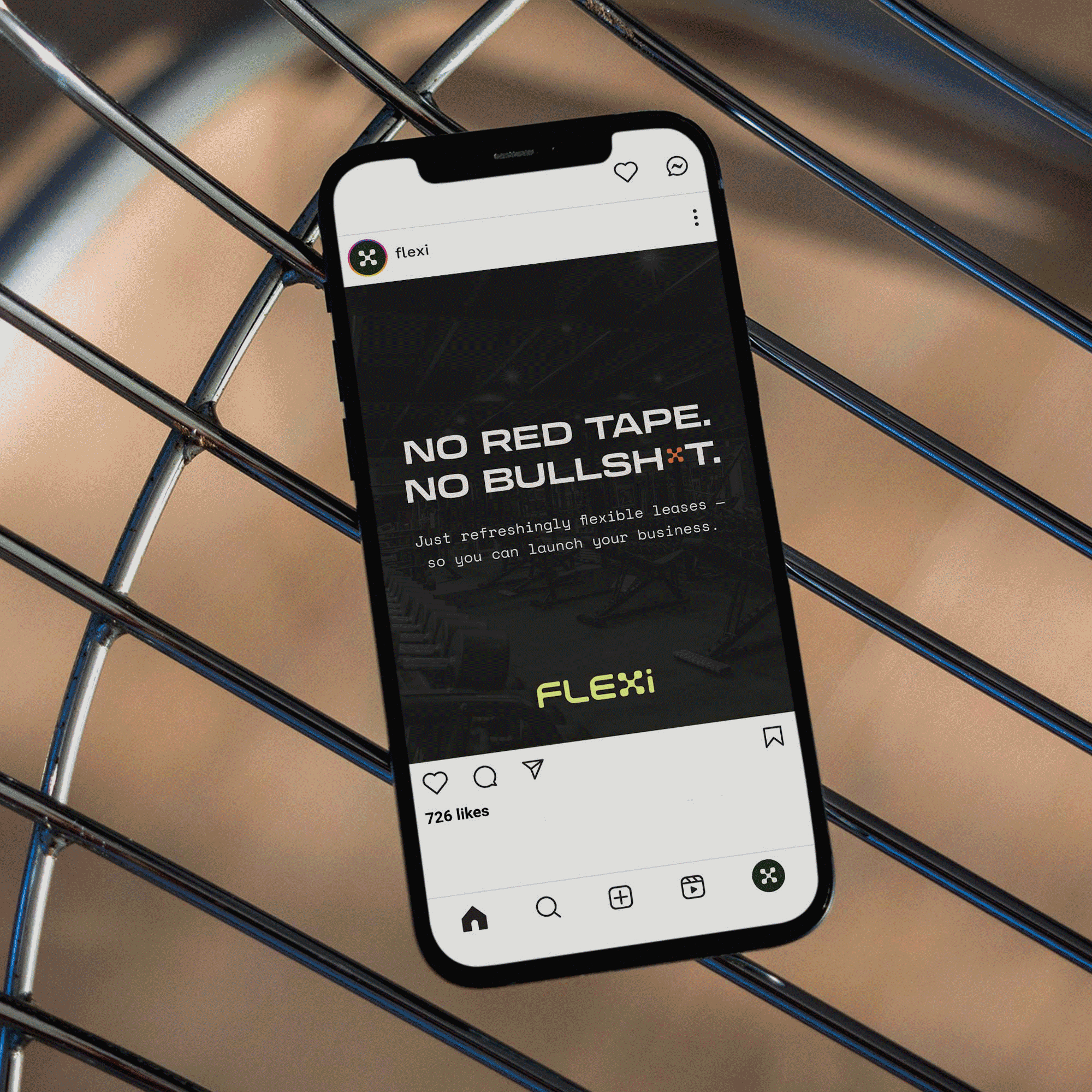 Smartphone displaying an advertisement for Flexi with the text 'No red tape. No bullshit.' and promoting flexible leases for launching businesses, resting on a metal grid surface.