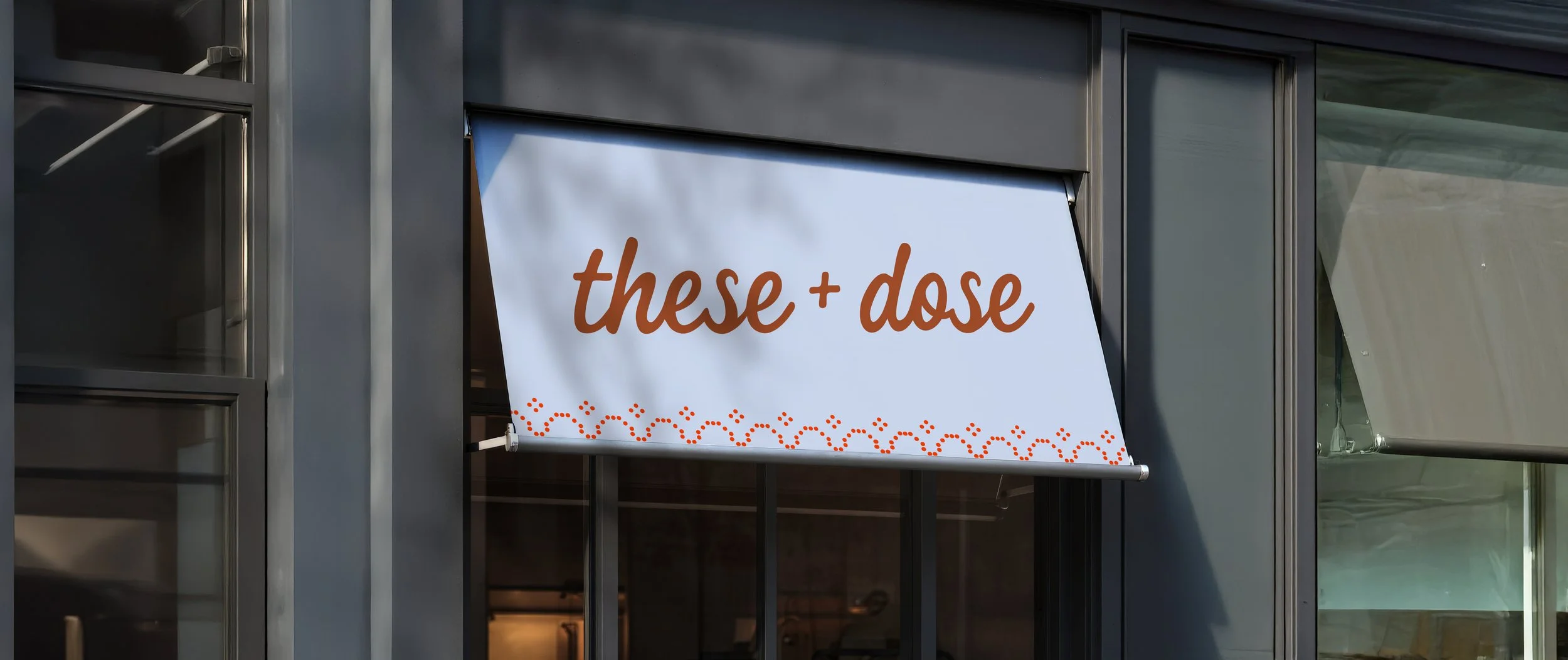 Signboard on building window with the words 'these + dose' in brown text and dotted decorative pattern underneath.