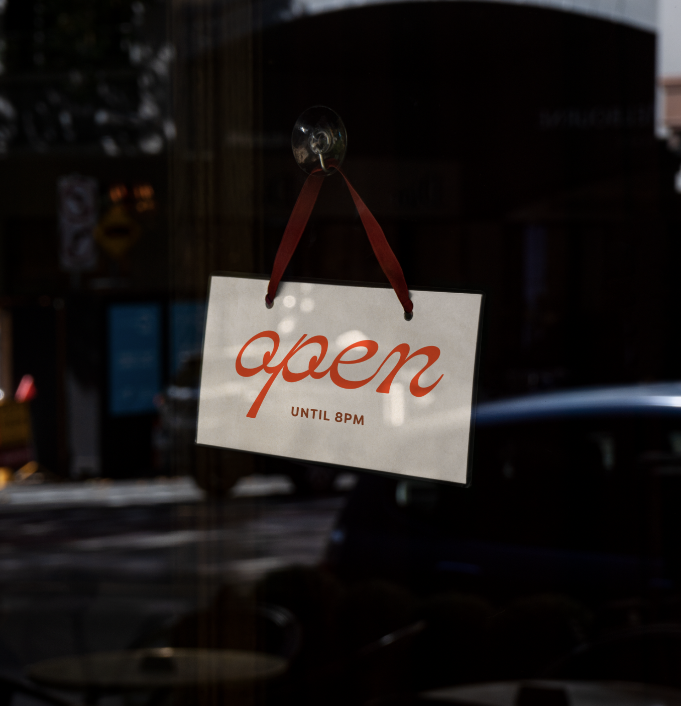 A sign hanging on a glass window with the word 'open' written in red cursive, indicating the business is open until 8 PM.