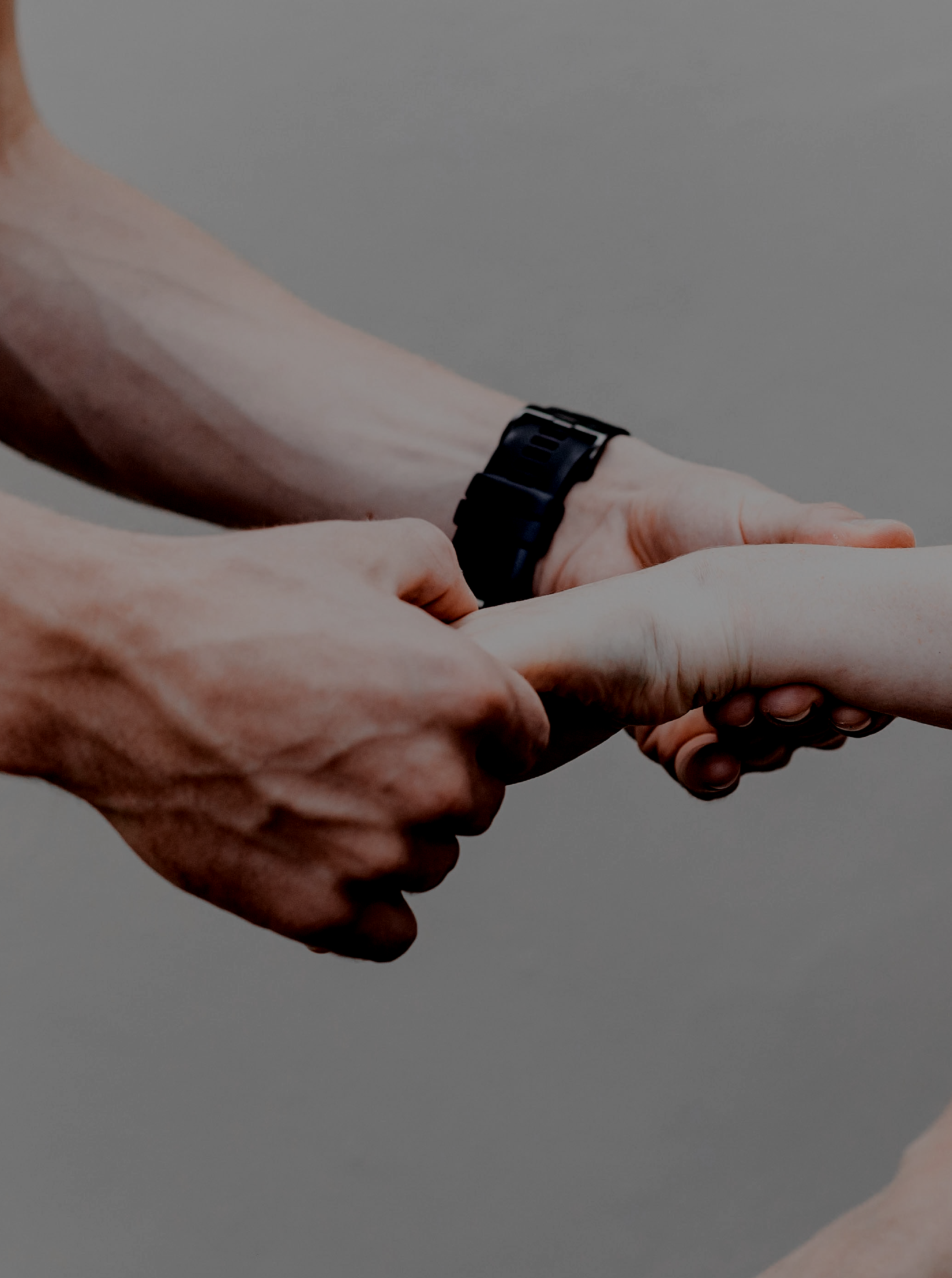 A person with a black watch holding another person's hand.