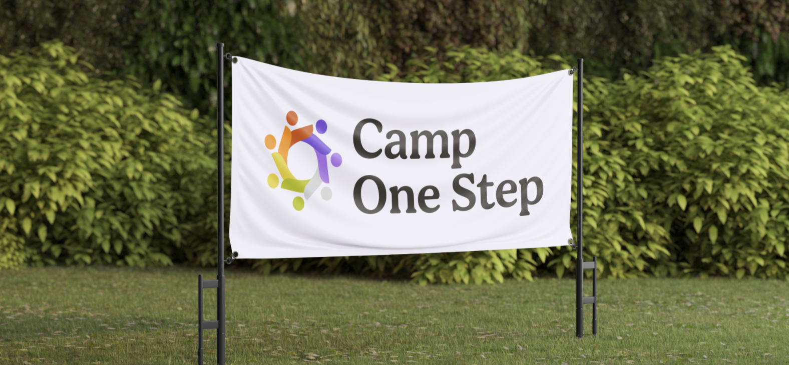 A white banner with the logo and text 'Camp One Step', set up outdoors on a grassy area with green bushes in the background.