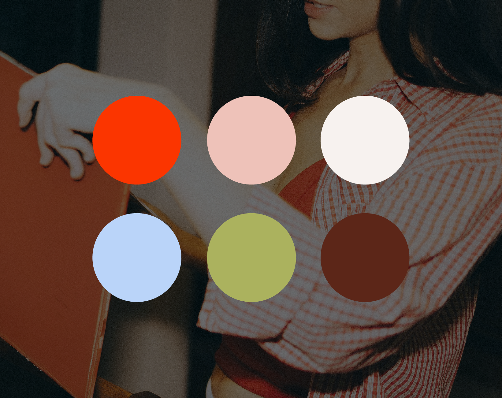 A woman wearing a red and white checkered shirt is holding an orange box, with her arms crossed. Several colored circles overlay the image, including red, pink, white, blue, green, and brown.