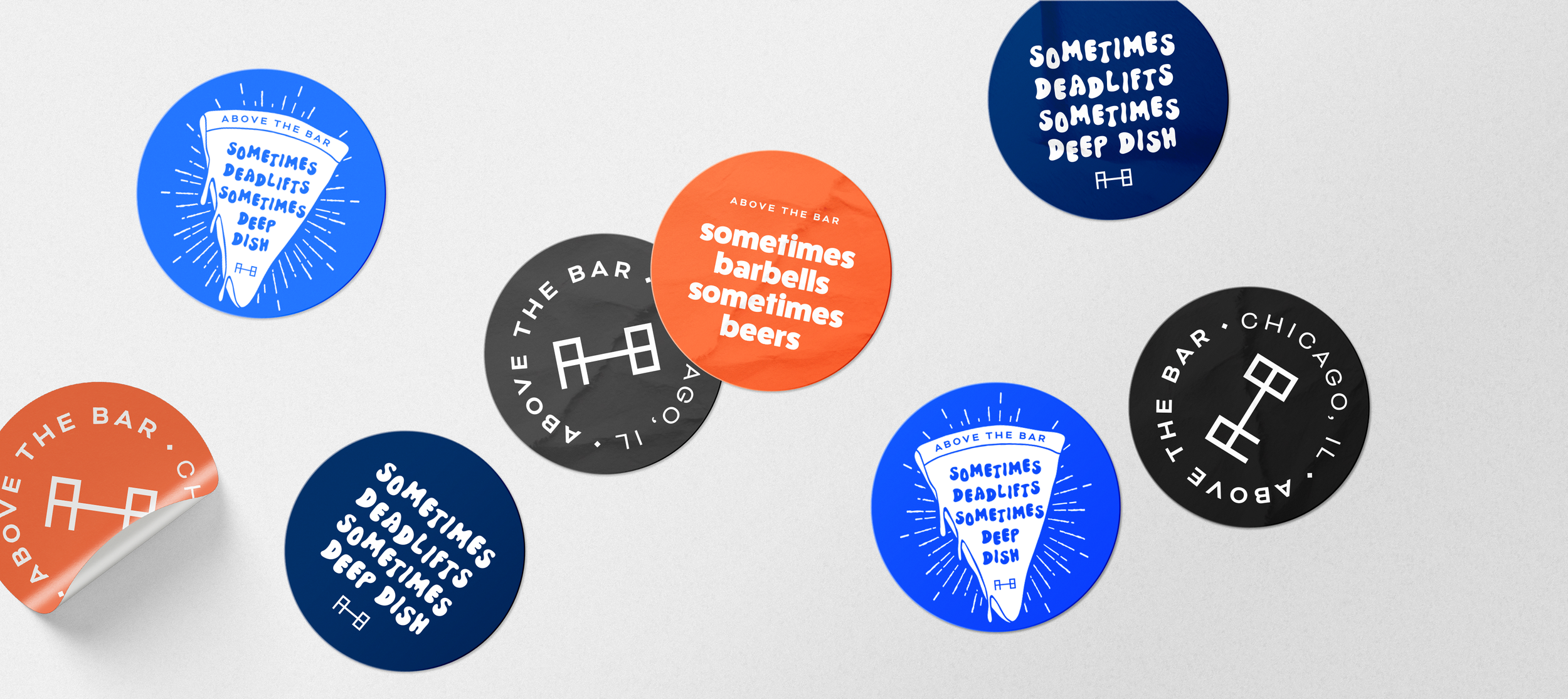 Collection of circular stickers with various colors and text related to a bar. The blue stickers say 'Sometimes deadlifts sometimes deep dish,' the orange ones say 'sometimes barbells sometimes beers,' and the black ones feature a barbell icon.