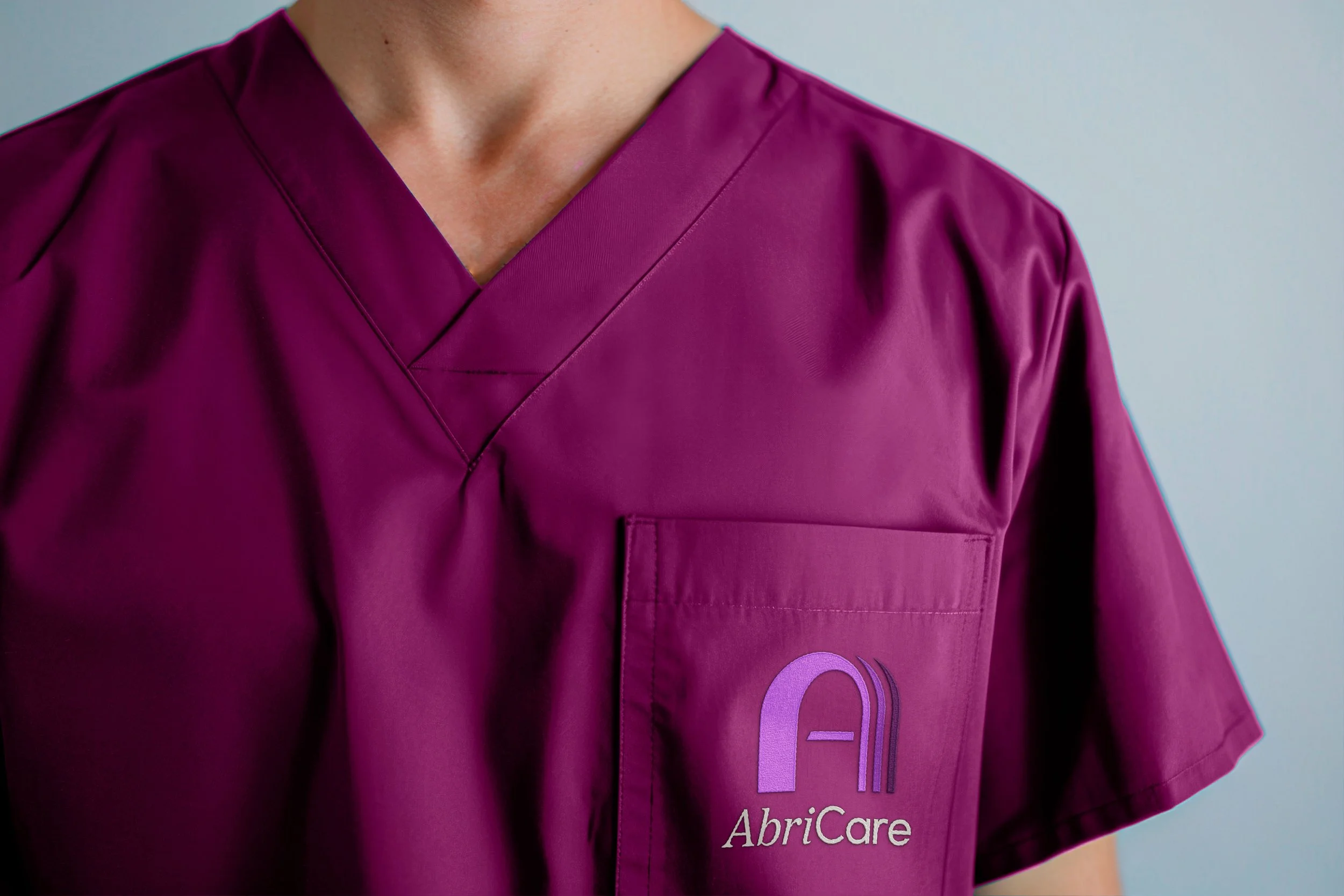 AbriCare logo on plum colored medical scrubs