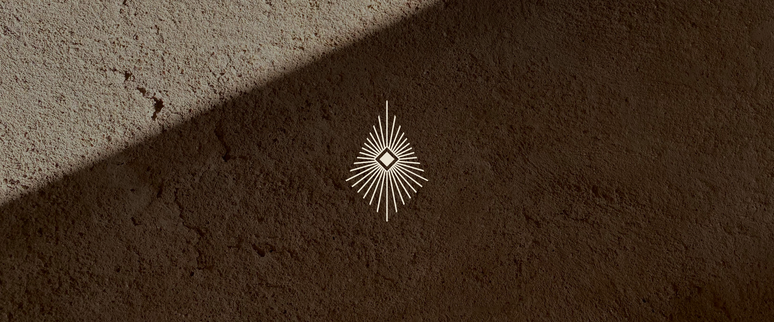 Close-up of a textured brown wall with a faint shadow and a white decorative geometric pattern in the center.