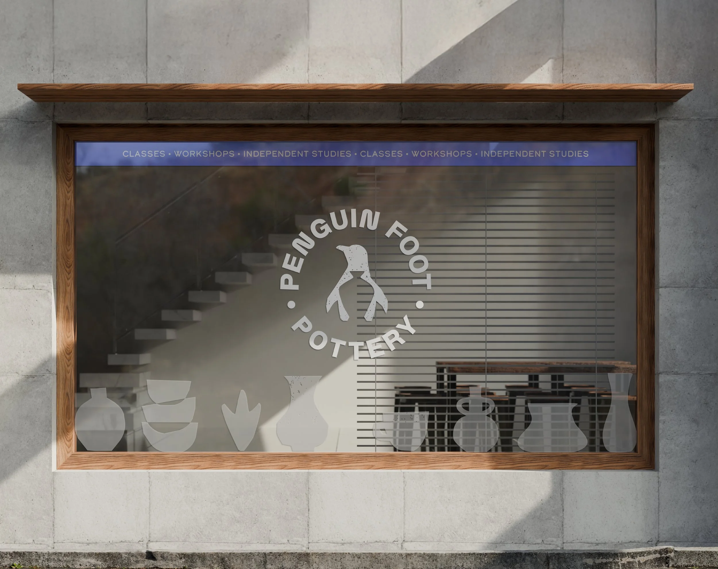 Storefront with a window displaying a logo featuring a penguin. Above the window, a blue banner lists 'Classes, Workshops, Independent Studies' repeated. The store appears to sell pottery, and the window has decorative fish and plant shapes.