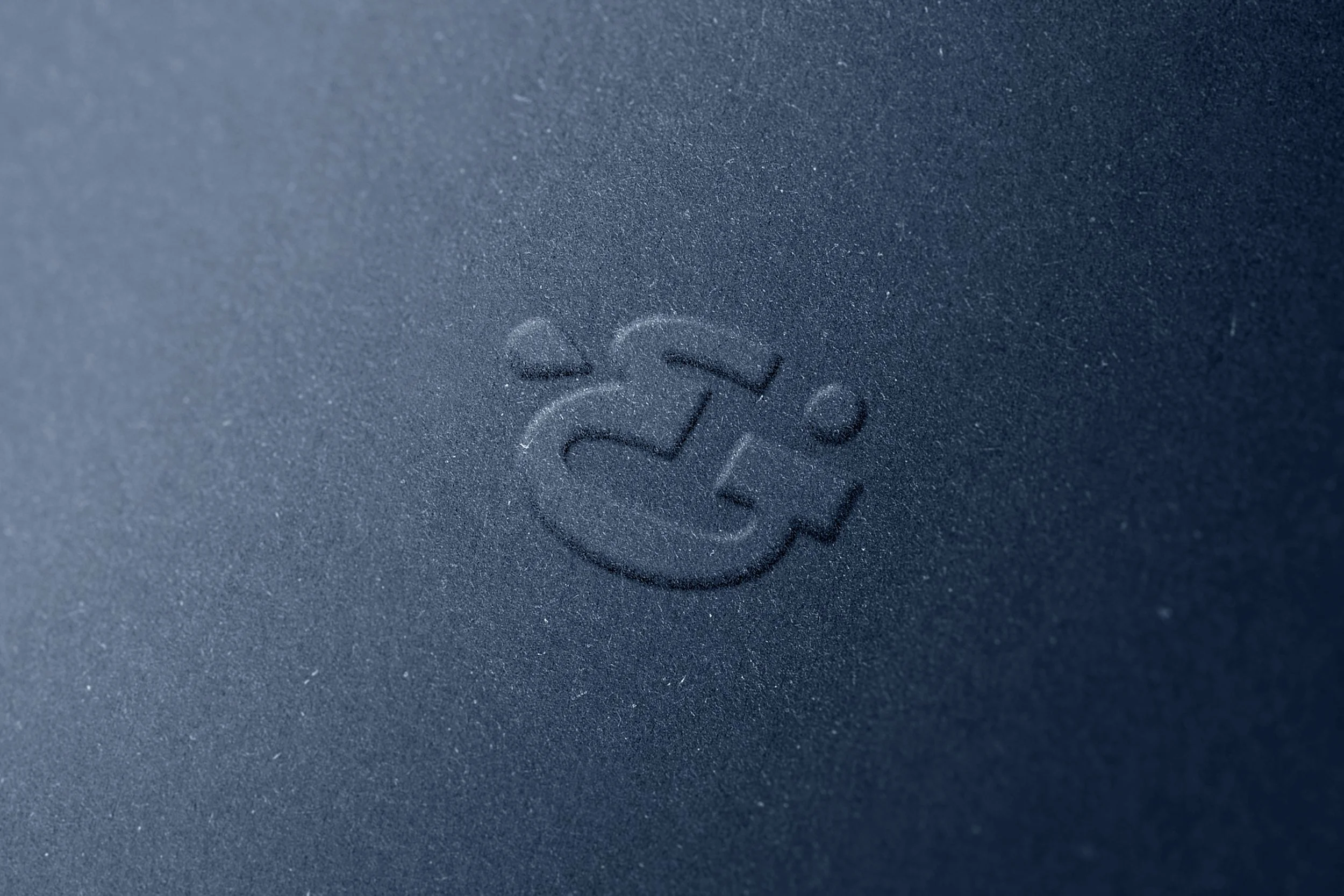 Close-up of a textured dark gray surface with an embossed logo for Harbor & Voyage.