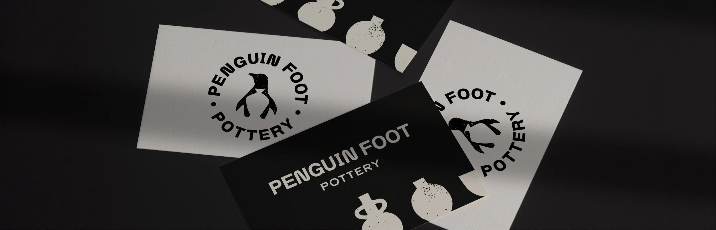 Business cards for Penguin Foot Pottery, one white with black text and logo, and one black with white text and logo, featuring a penguin silhouette.