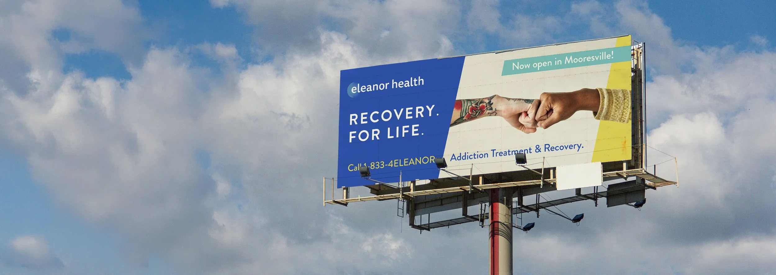 Billboard advertising Eleanor Health addiction treatment with colorful handshake imagery, blue and yellow background, and contact information, now open in Mooresville.