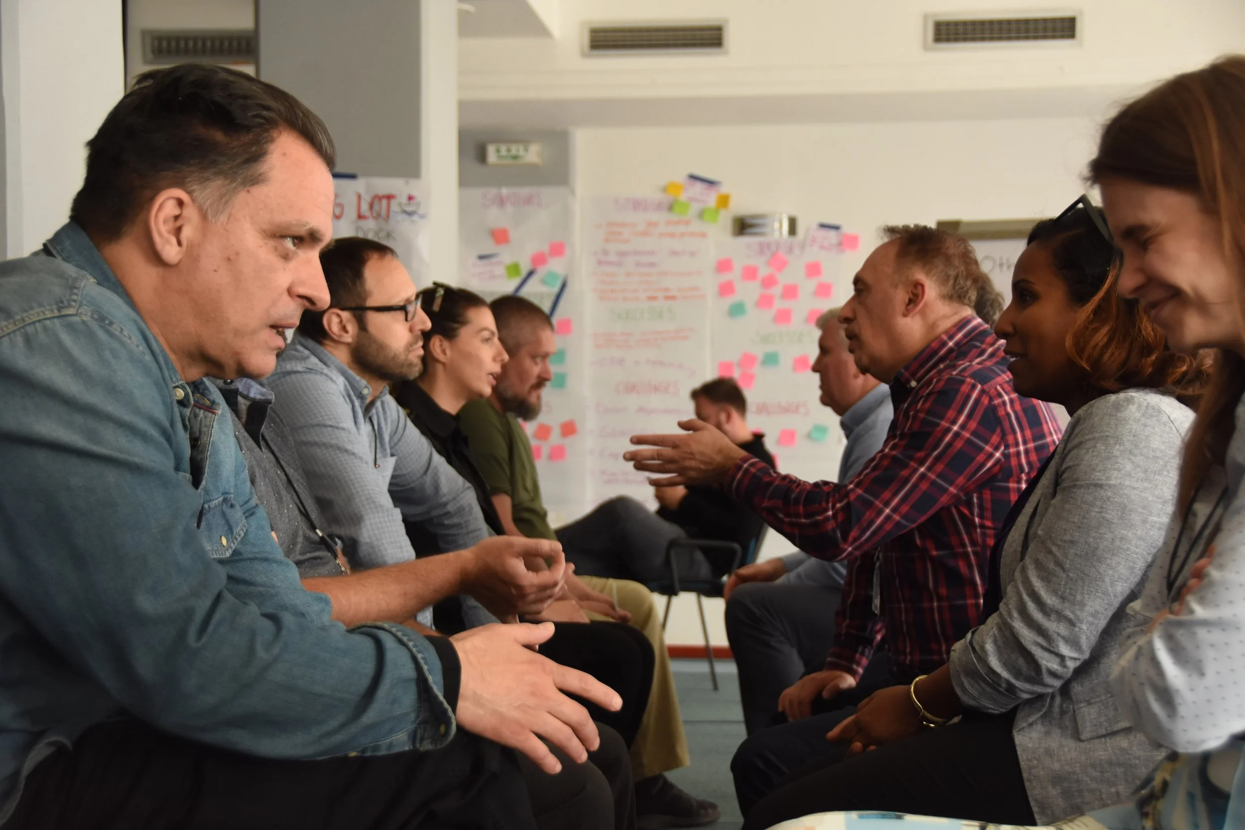 People sitting in two parallel rows engaging in a discussion during a regional learning summit convening locally led development practitioners from countries across the Balkans region.