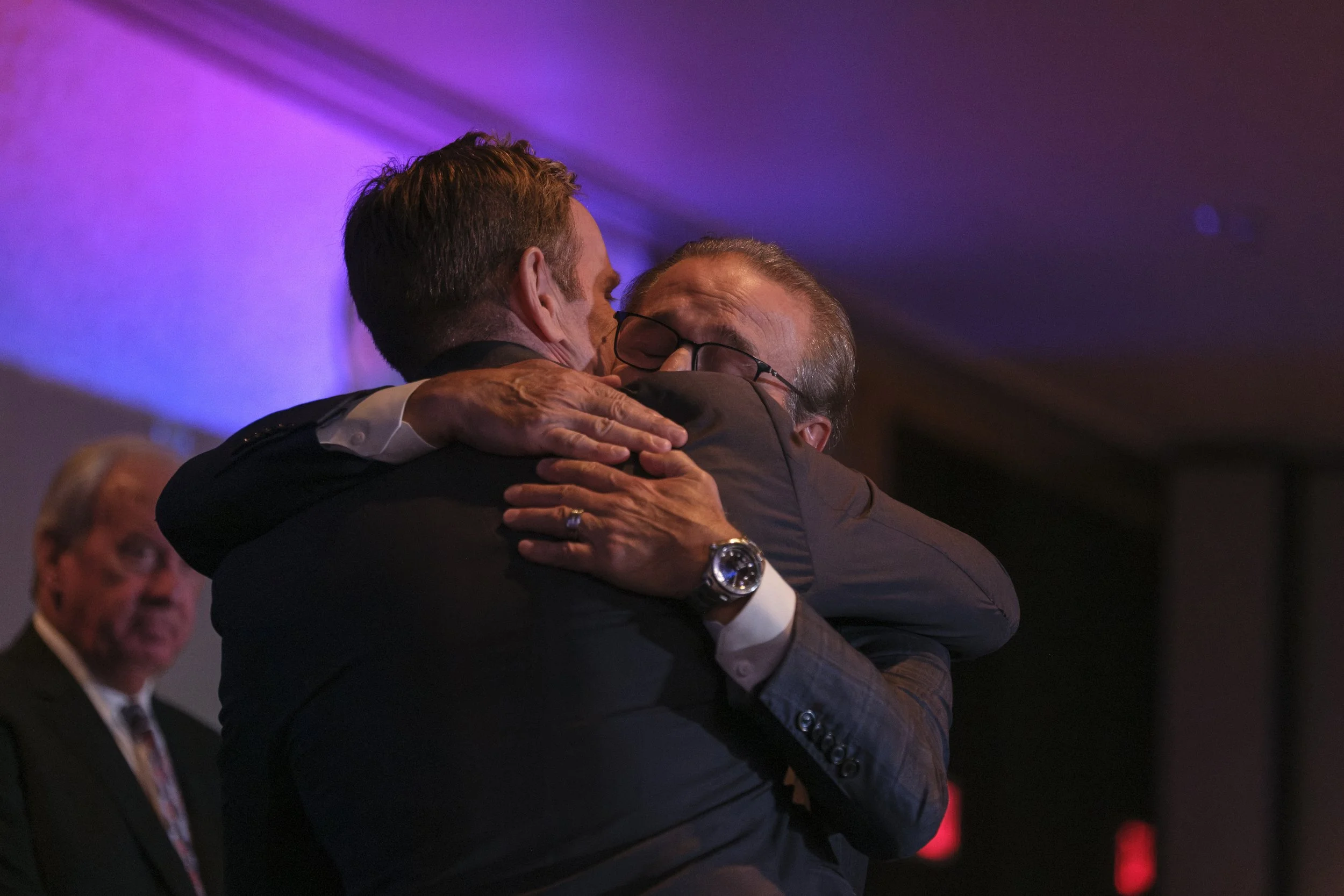 Ken Daniels hugs a survivor of substance abuse on stage during the roast of Chris Osgood.