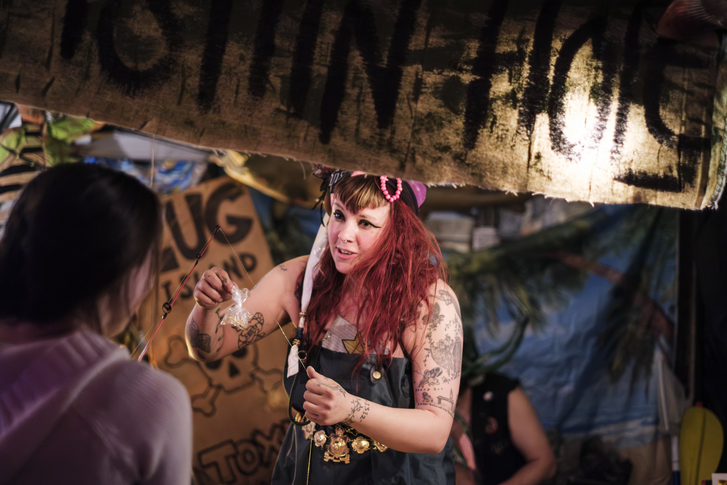 A Dumpy Dicker Ypsitucky Travelin' Carnival member, dressed as a fisherman, interacts with a patron.